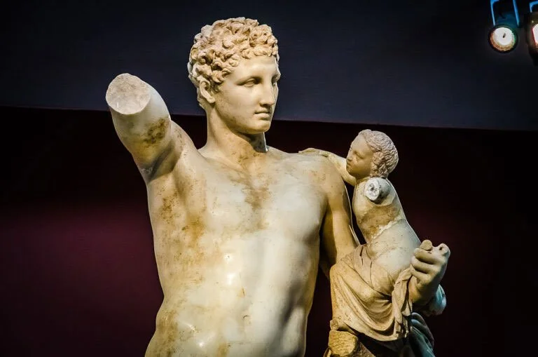 Close view of a marble Hermes figure holding the infant Dionysus, with the child turned toward him.