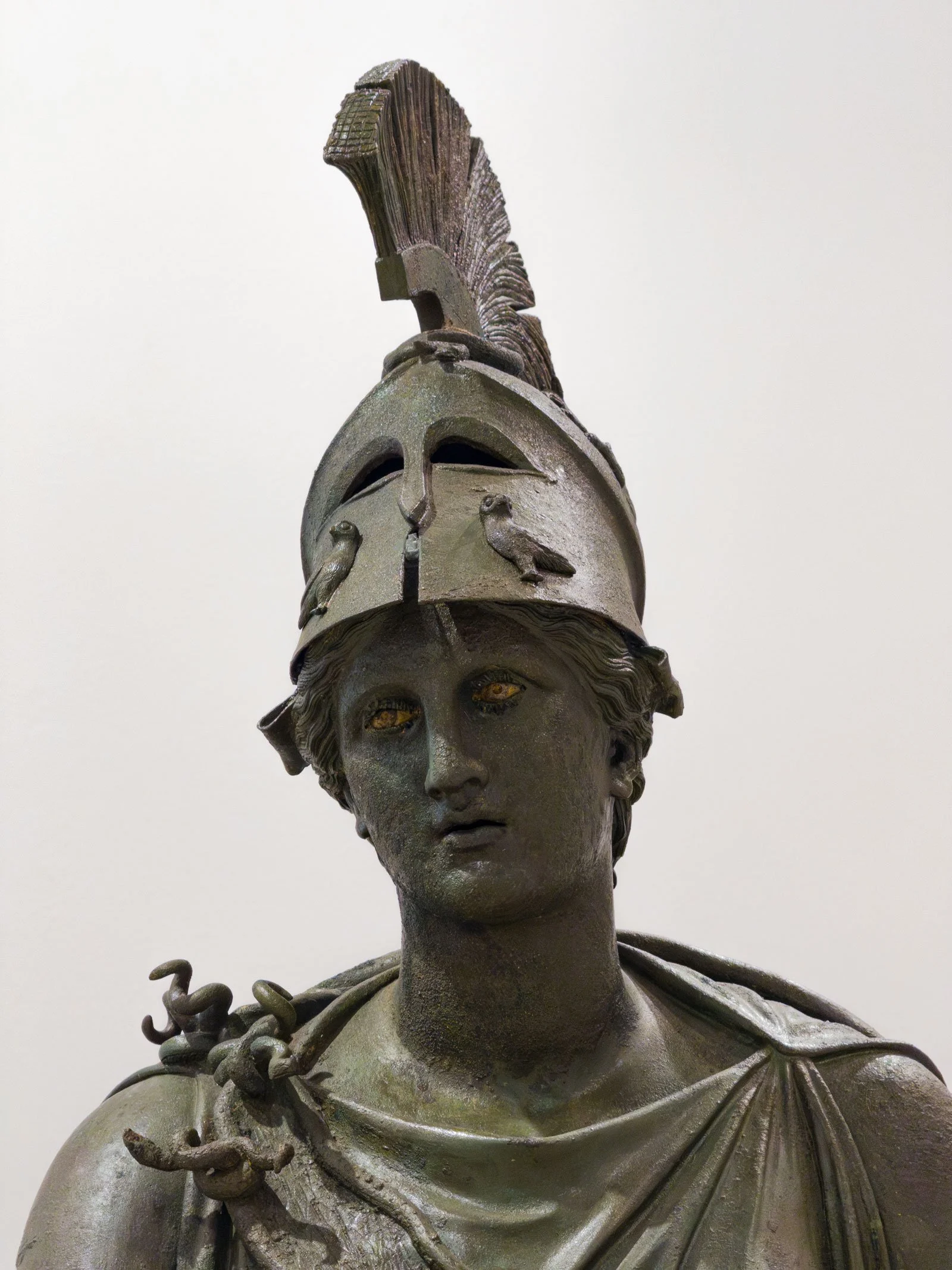 Close-up of a bronze Athena head wearing a crested helmet.