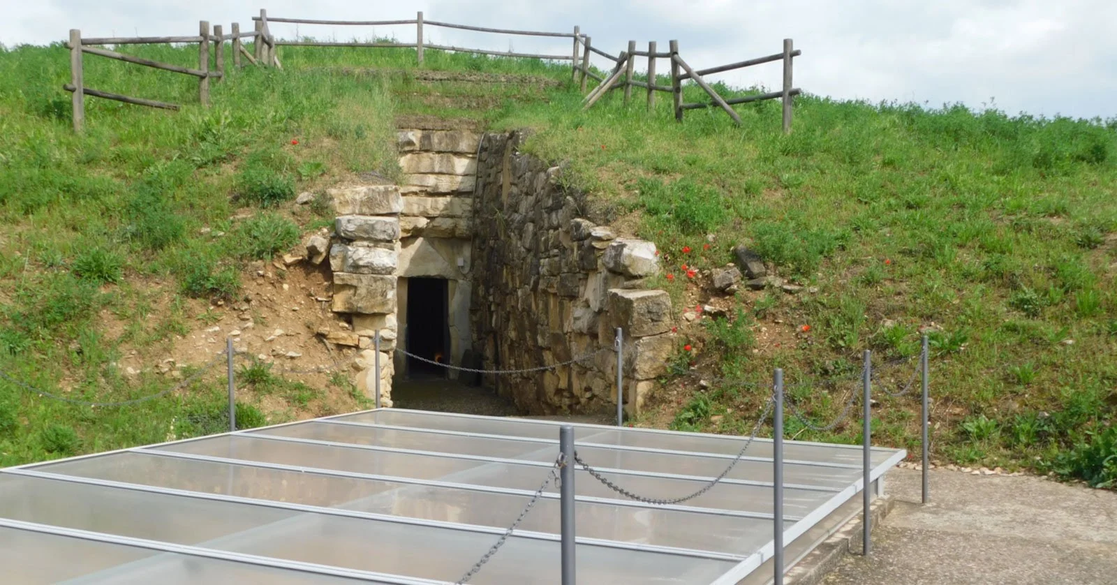 Monumental burial mound with a stone-lined entrance passage cut into the earth.