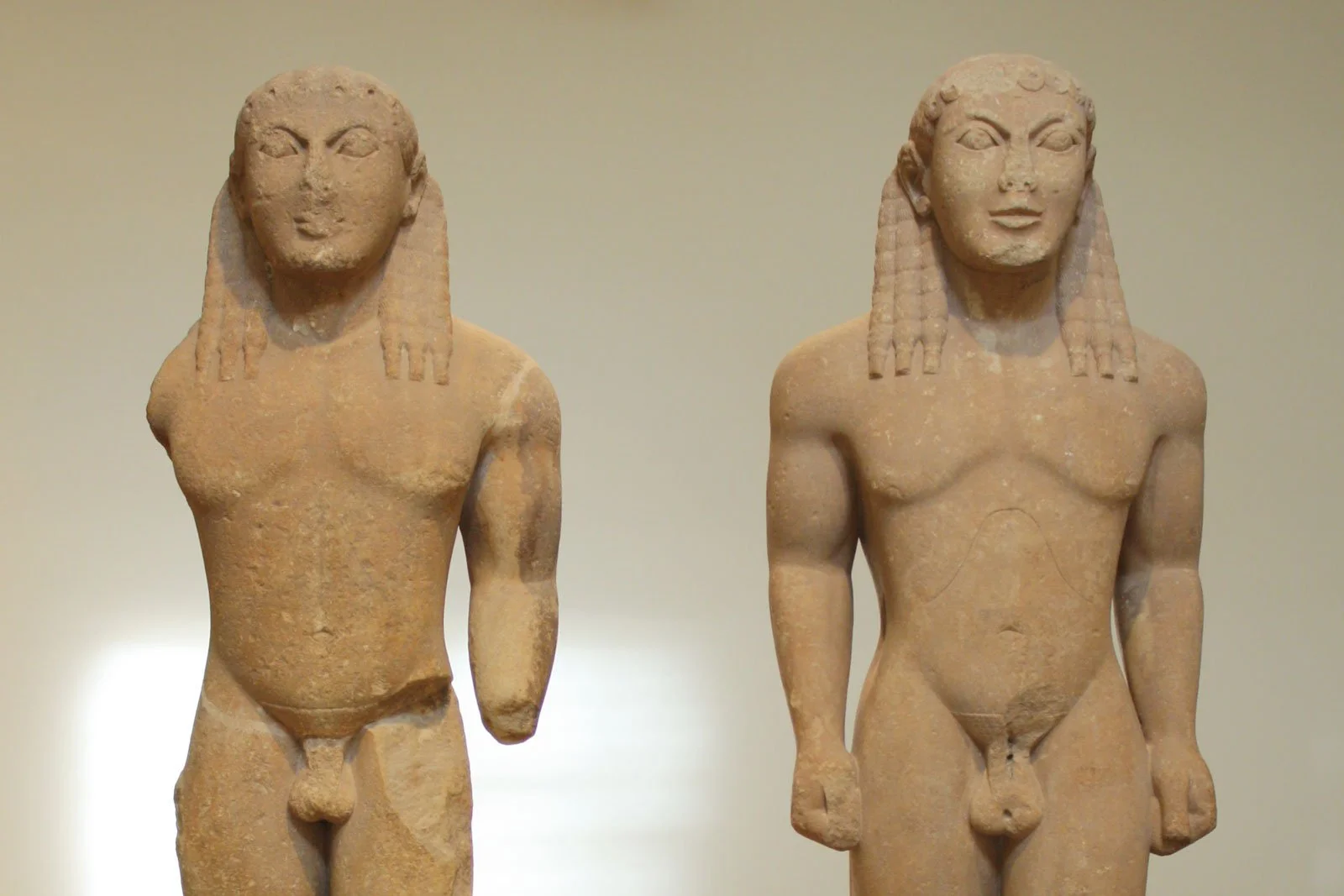 Two large archaic kouros statues standing side by side on a shared base.