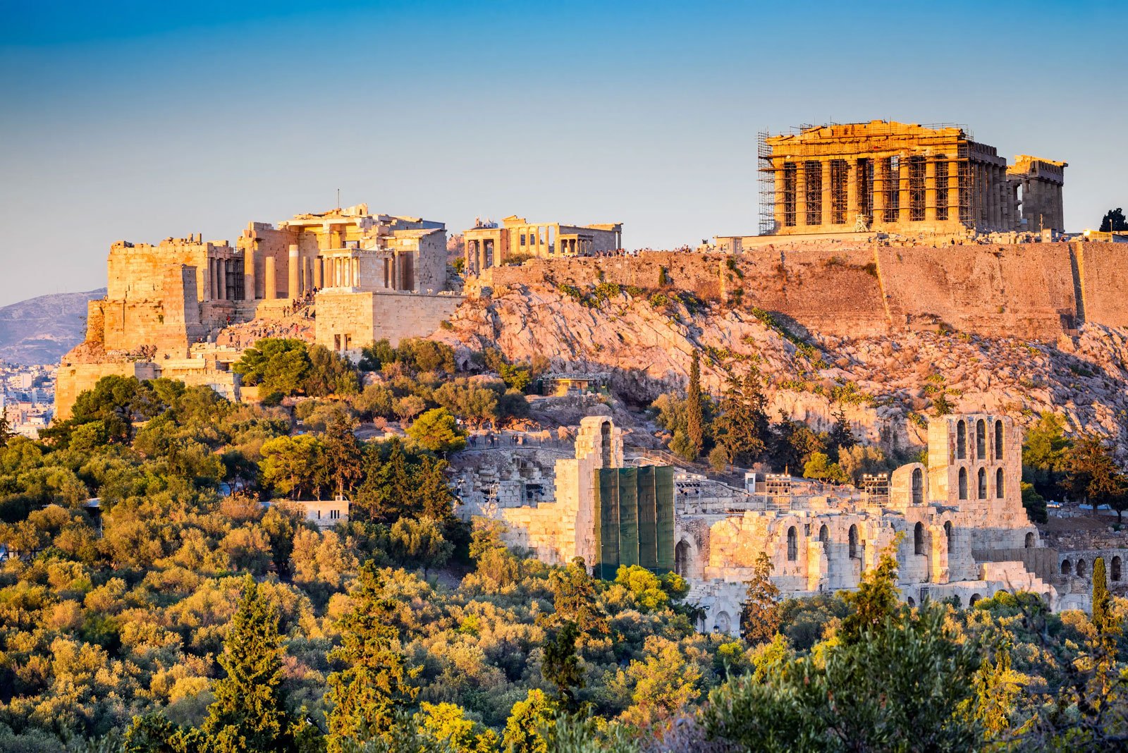 Panoramic view of the Acropolis in Athens with the Parthenon lit by warm light above the city.