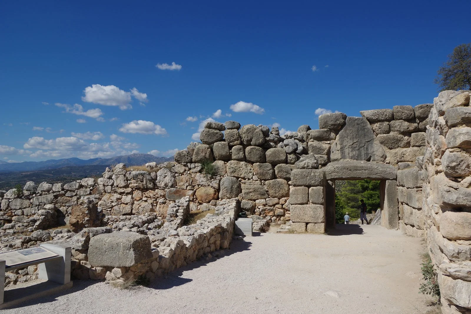 View of Cyclopean stone walls and rear of a gateway at Mycenae under a blue sky.