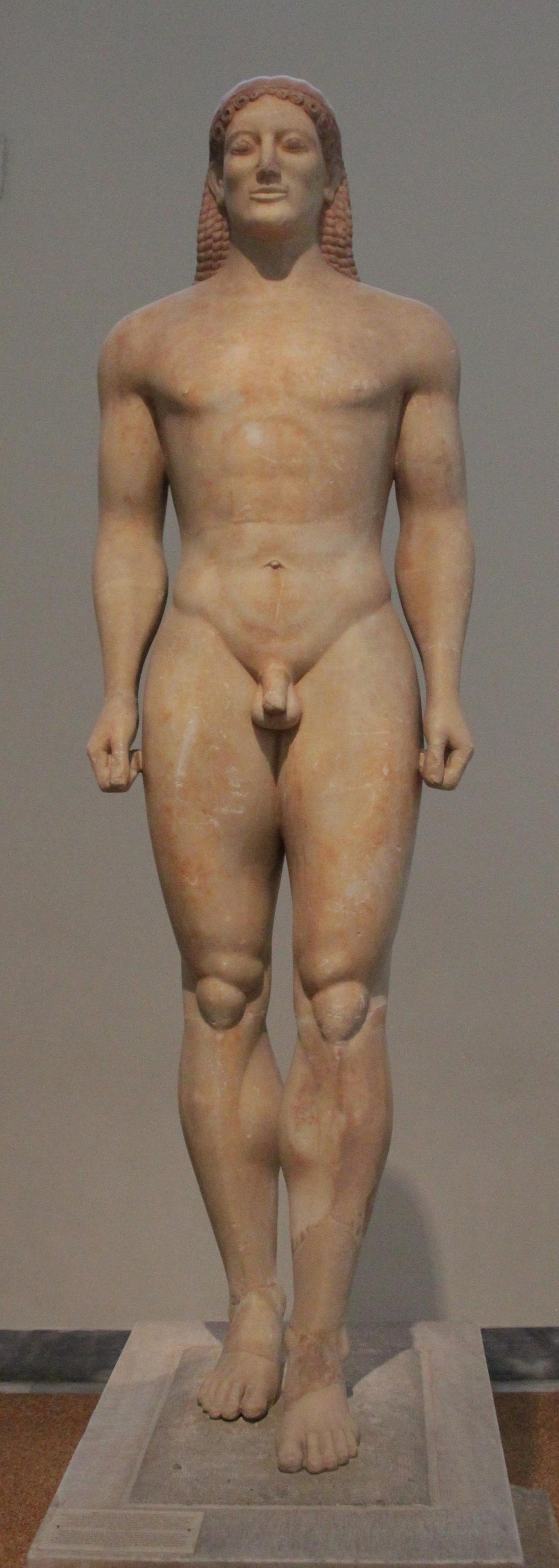 Anavysos Kouros, an idealised nude youth standing rigidly with one leg advanced, archaic smile and faint traces of red pigment.