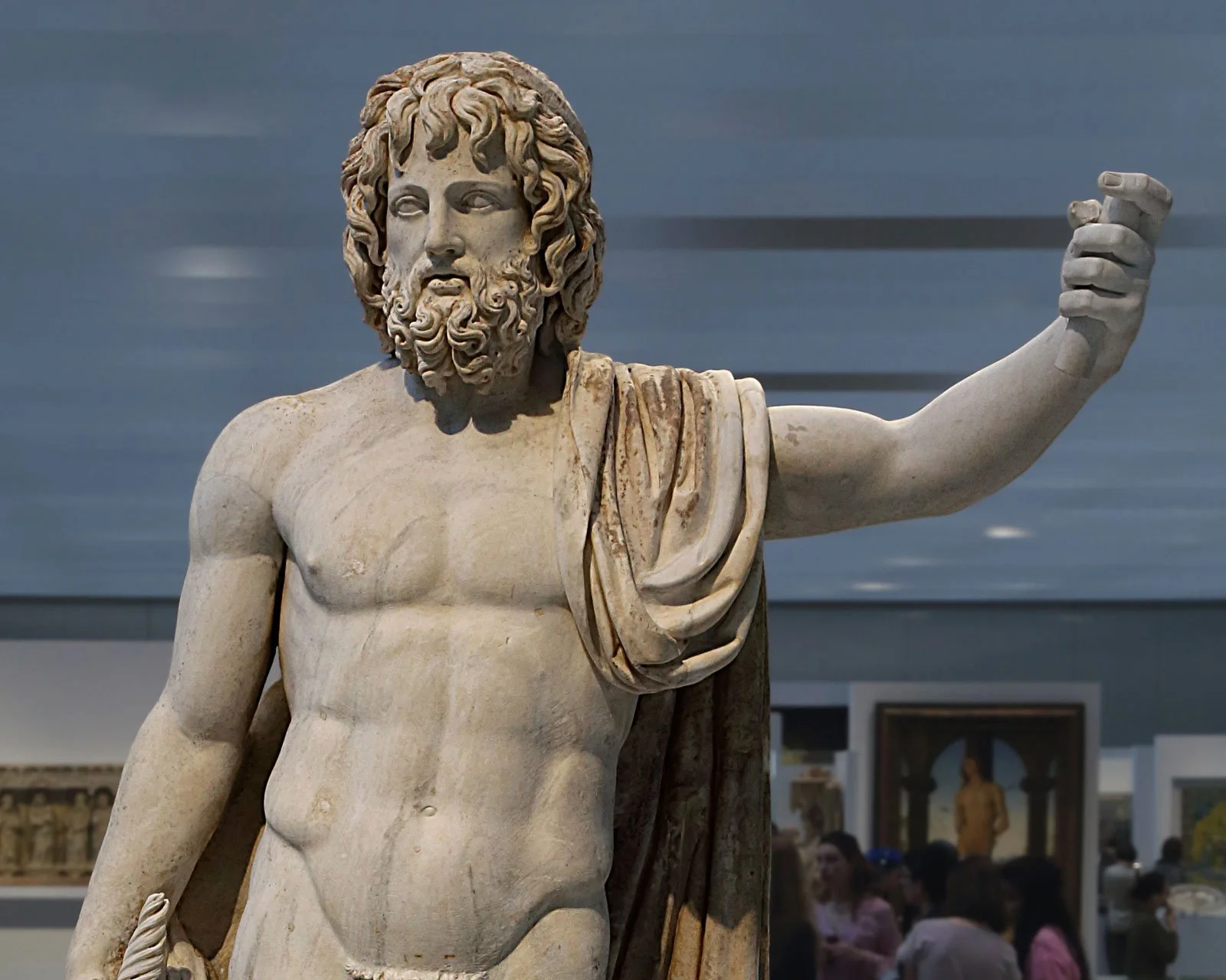 Close-up of a bearded Zeus or Jupiter statue with one arm raised.