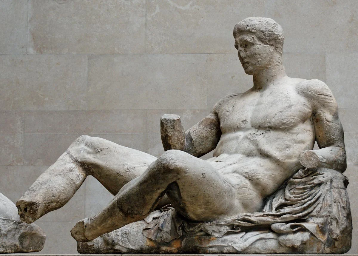 Reclining male figure from the Parthenon pediment displayed in a museum.