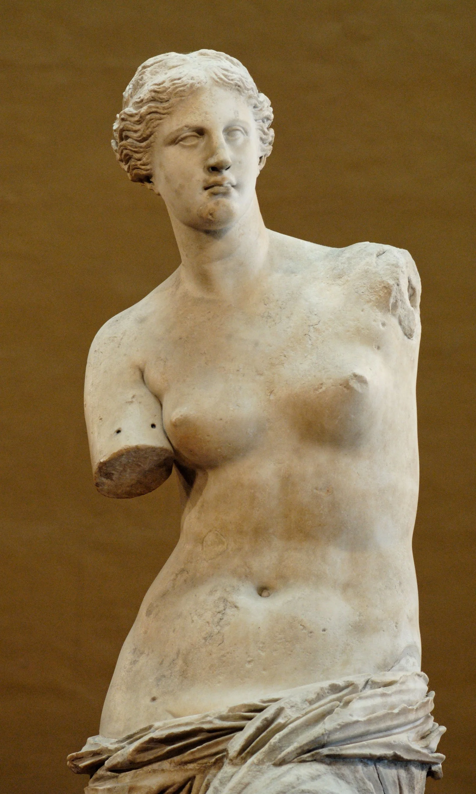 Full view of the Venus de Milo standing with missing arms and drapery around her hips.