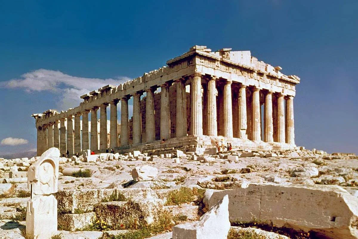 Wide view of the Parthenon surrounded by broken marble blocks on the Acropolis.