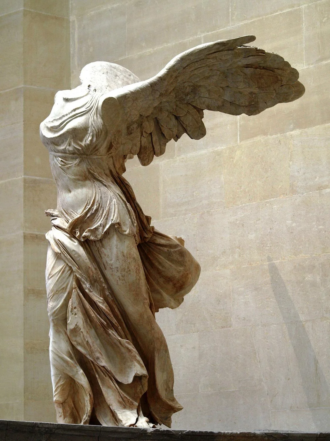 The Winged Victory (Nike) poised as if landing, with wings spread and drapery swept by wind.