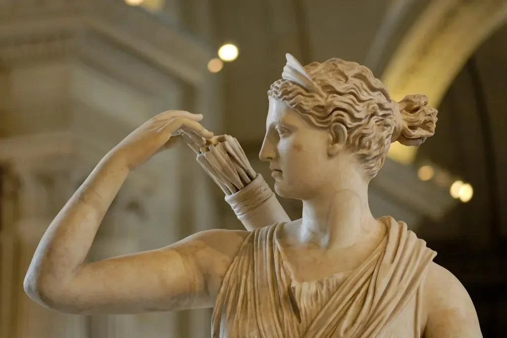 Detail of the Diana of Versailles, marble goddess in motion, drawing an arrow with swirling drapery in the Louvre museum.