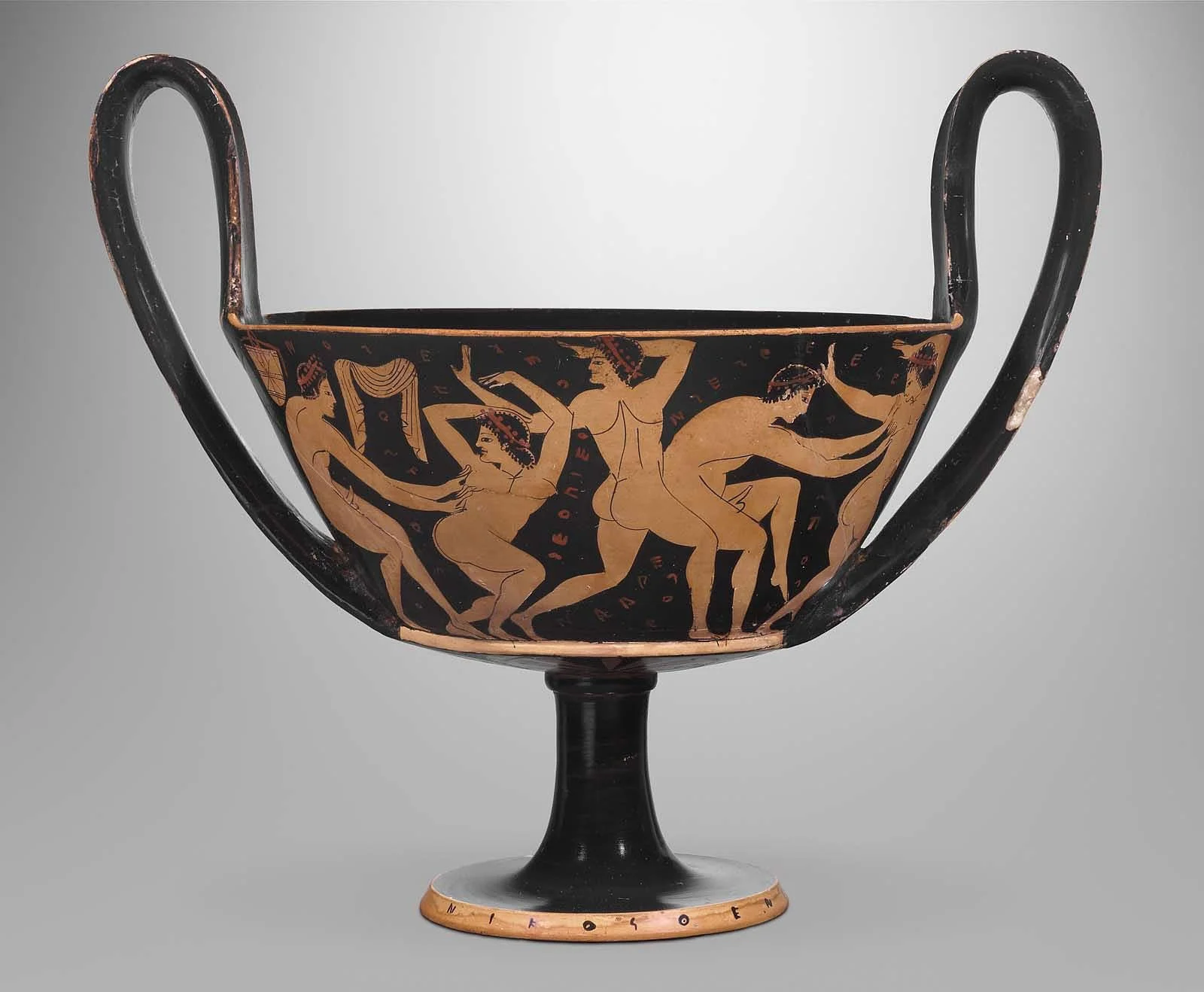Black-figure kantharos with tall handles and painted figures on a pale background.