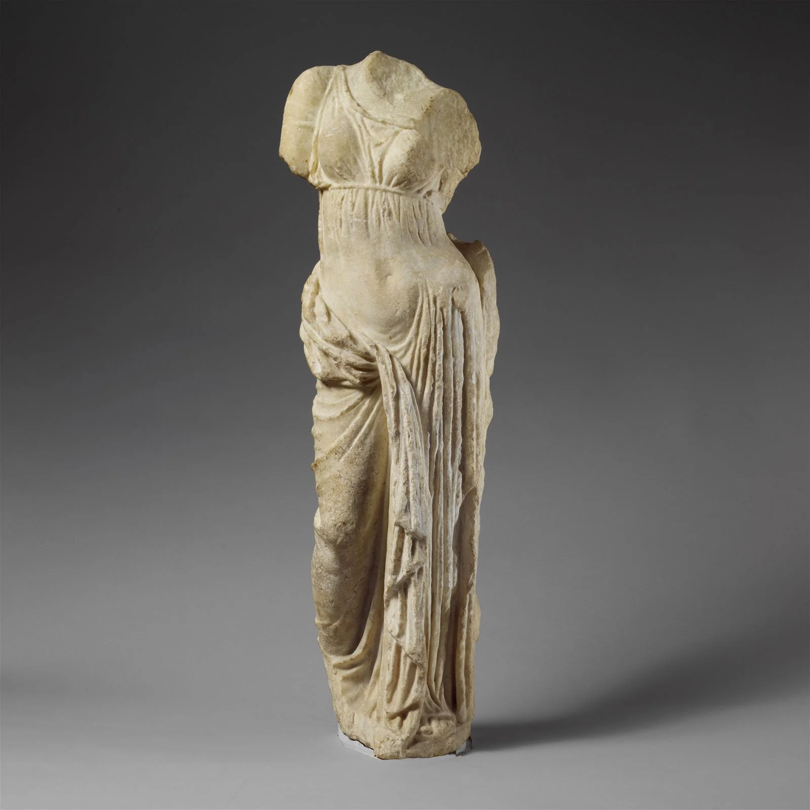 Fragmentary marble statue of Aphrodite with missing head and arms and drapery over the lower body.