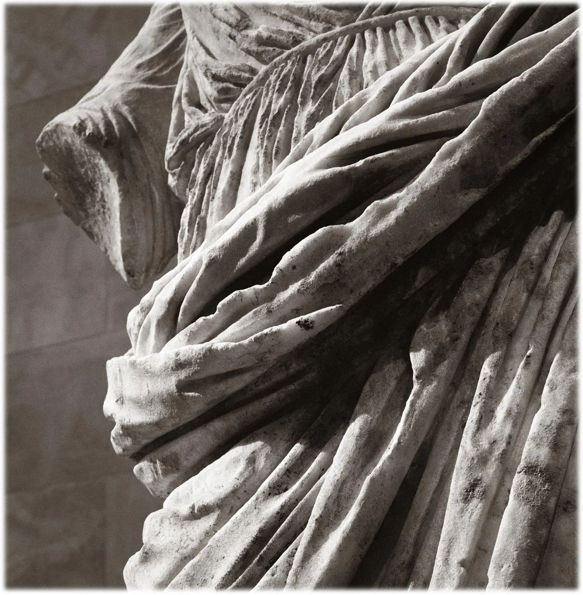 Close-up detail of marble drapery with deep, layered folds and sharp ridges.