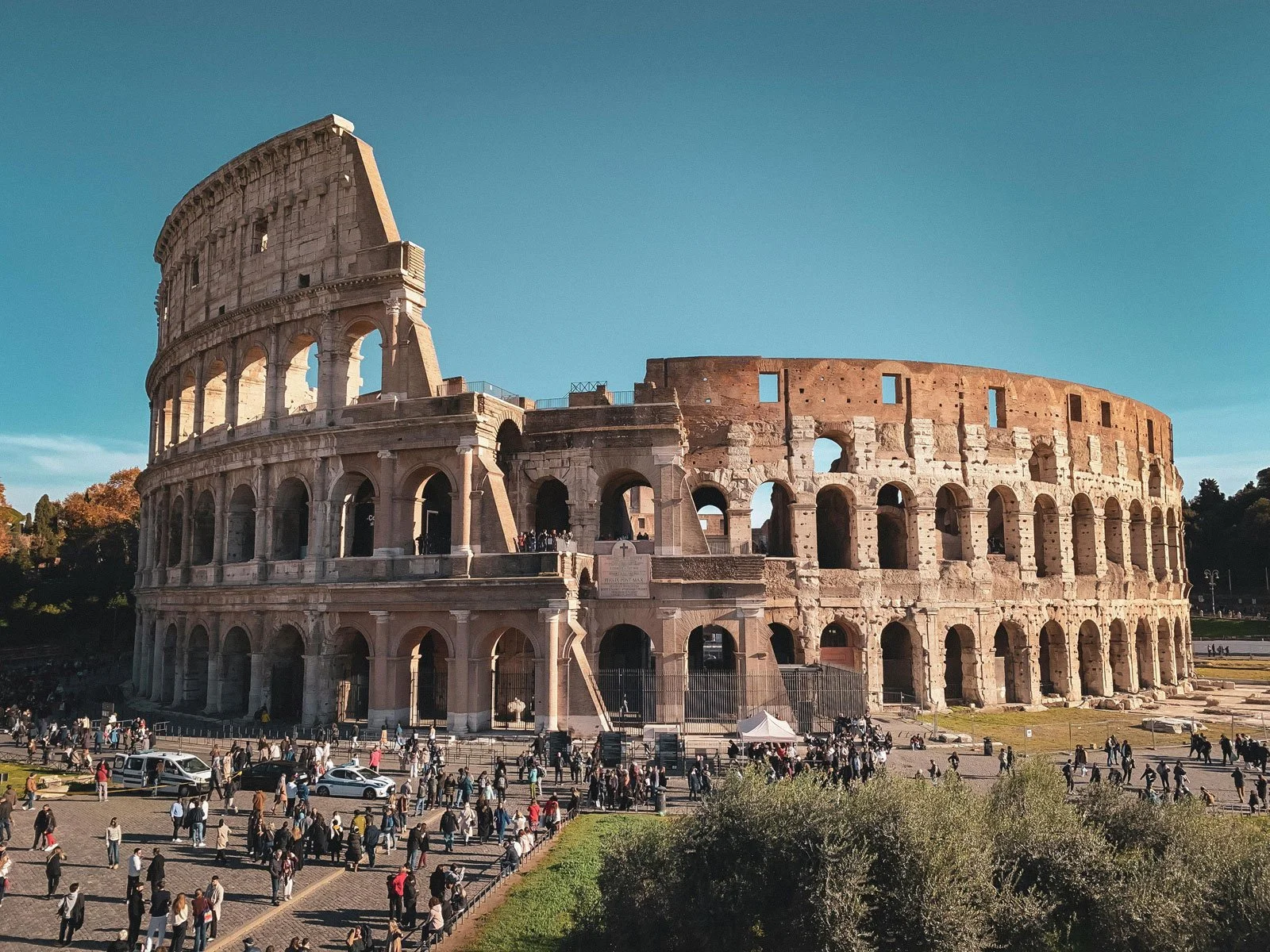 Exterior view of the Colosseum in Rome showing its massive elliptical shell and stacked arcades.
