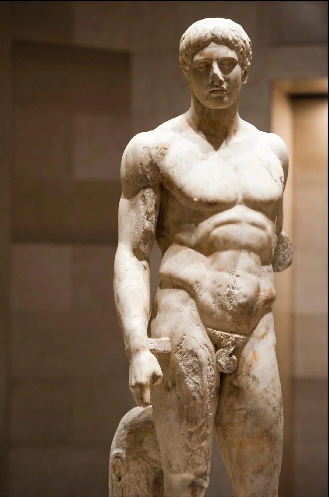 Marble statue of a young male with a slight contrapposto stance and missing arms.