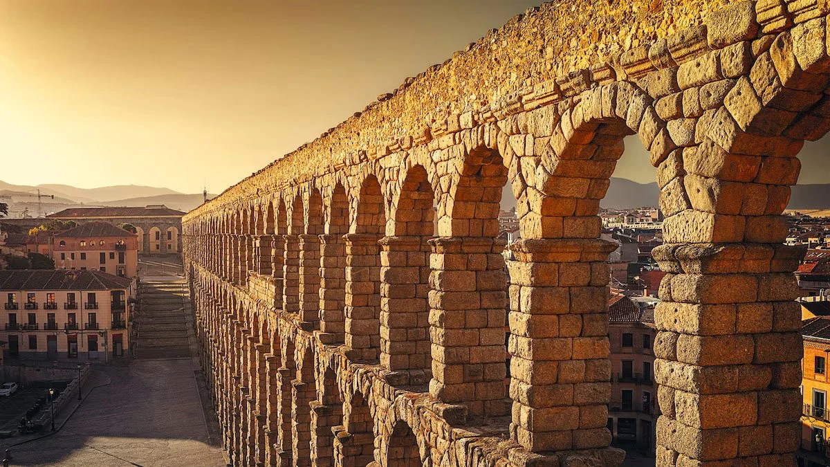 Close angled view of the Aqueduct of Segovia with repeated stone arches above the city.