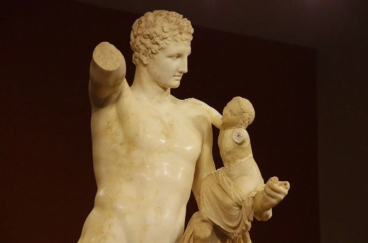 Marble statue of Hermes holding the infant Dionysus beside him.