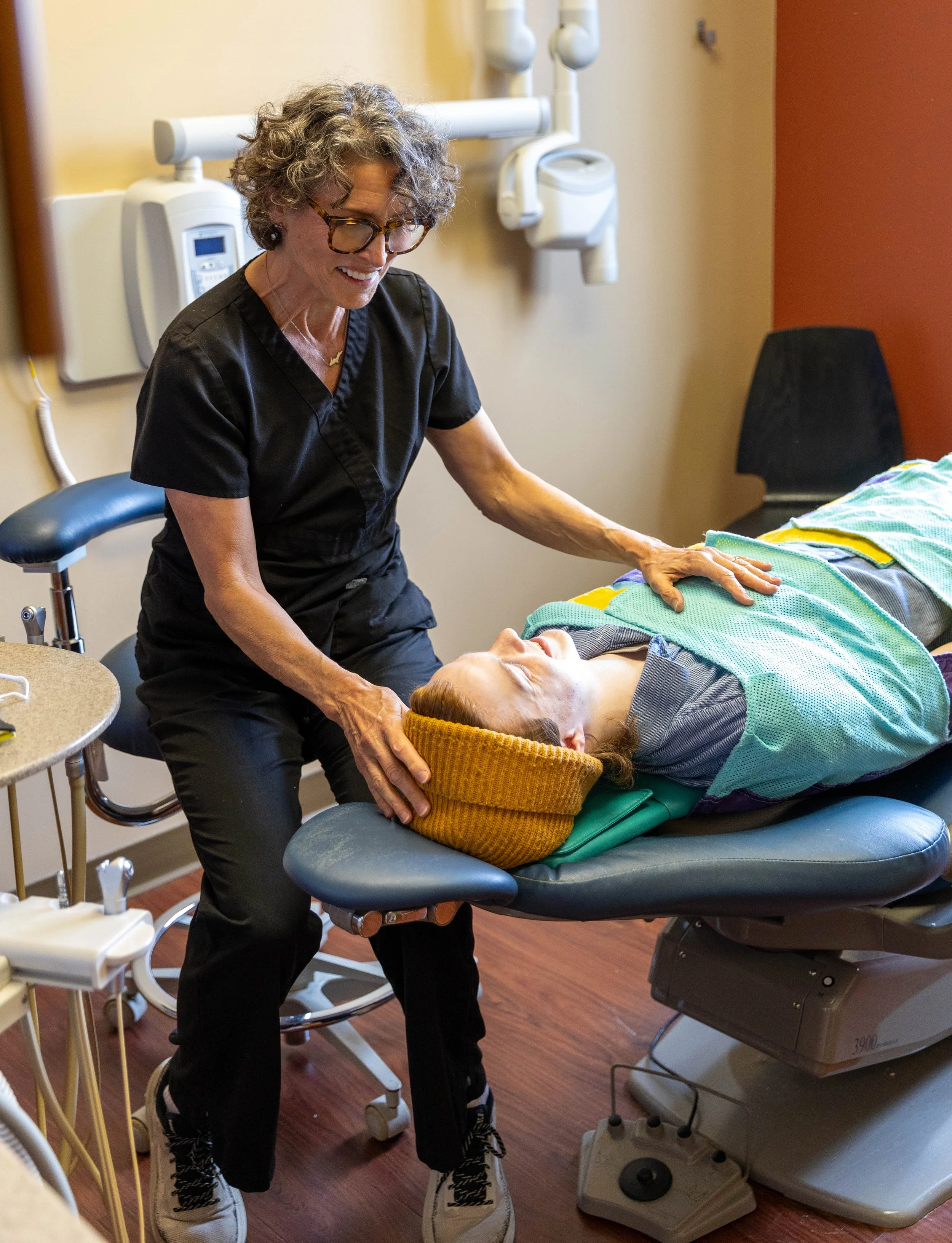 A healthcare professional performing a physical examination on a patient lying on a medical bed in a clinic room.