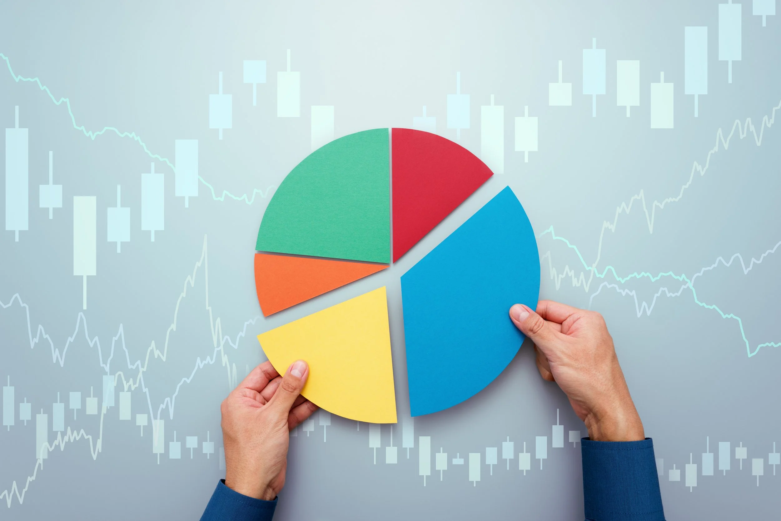 Person holding pieces of a pie chart with financial data in the background.