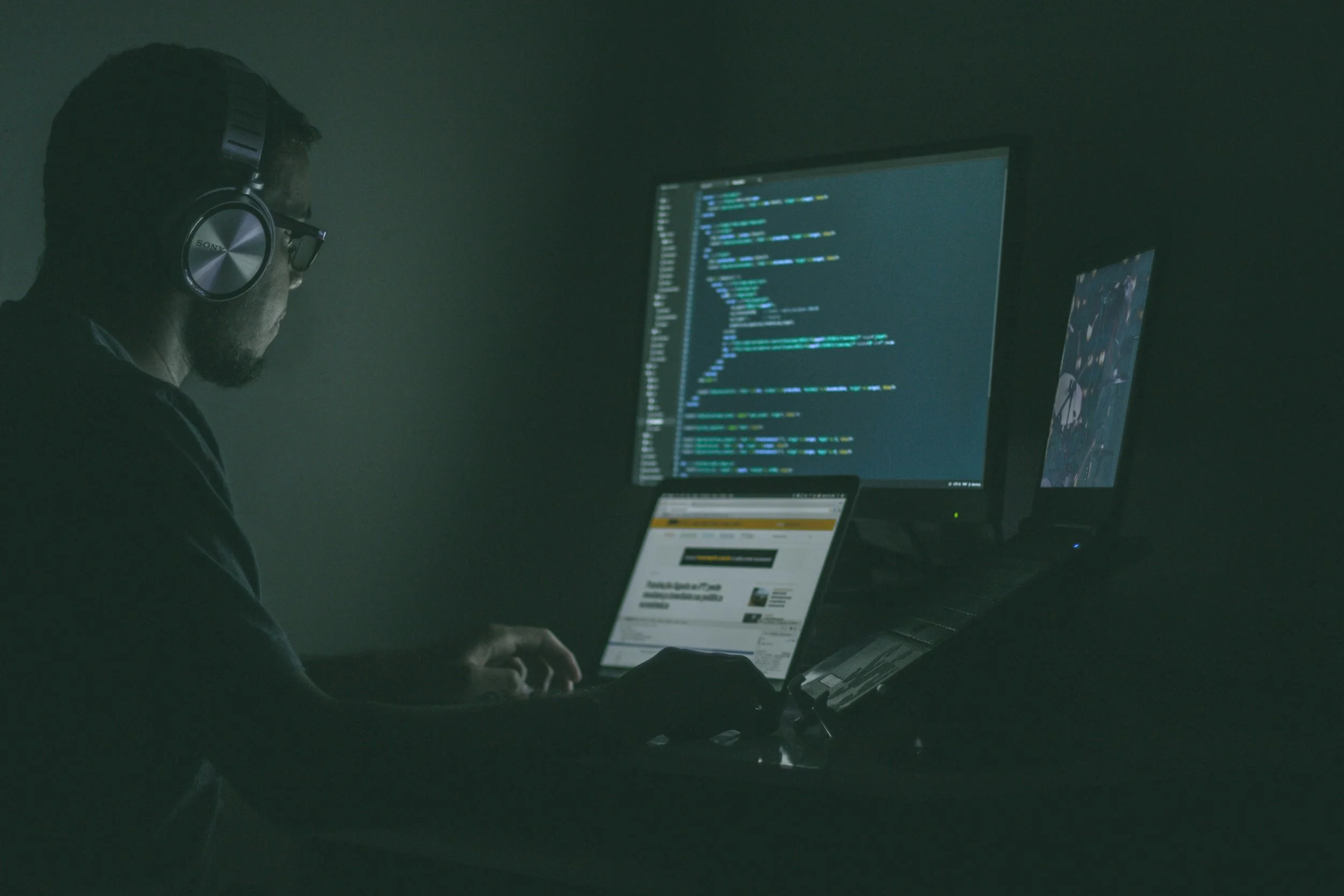 Developer in a dark room looking at code from a website..