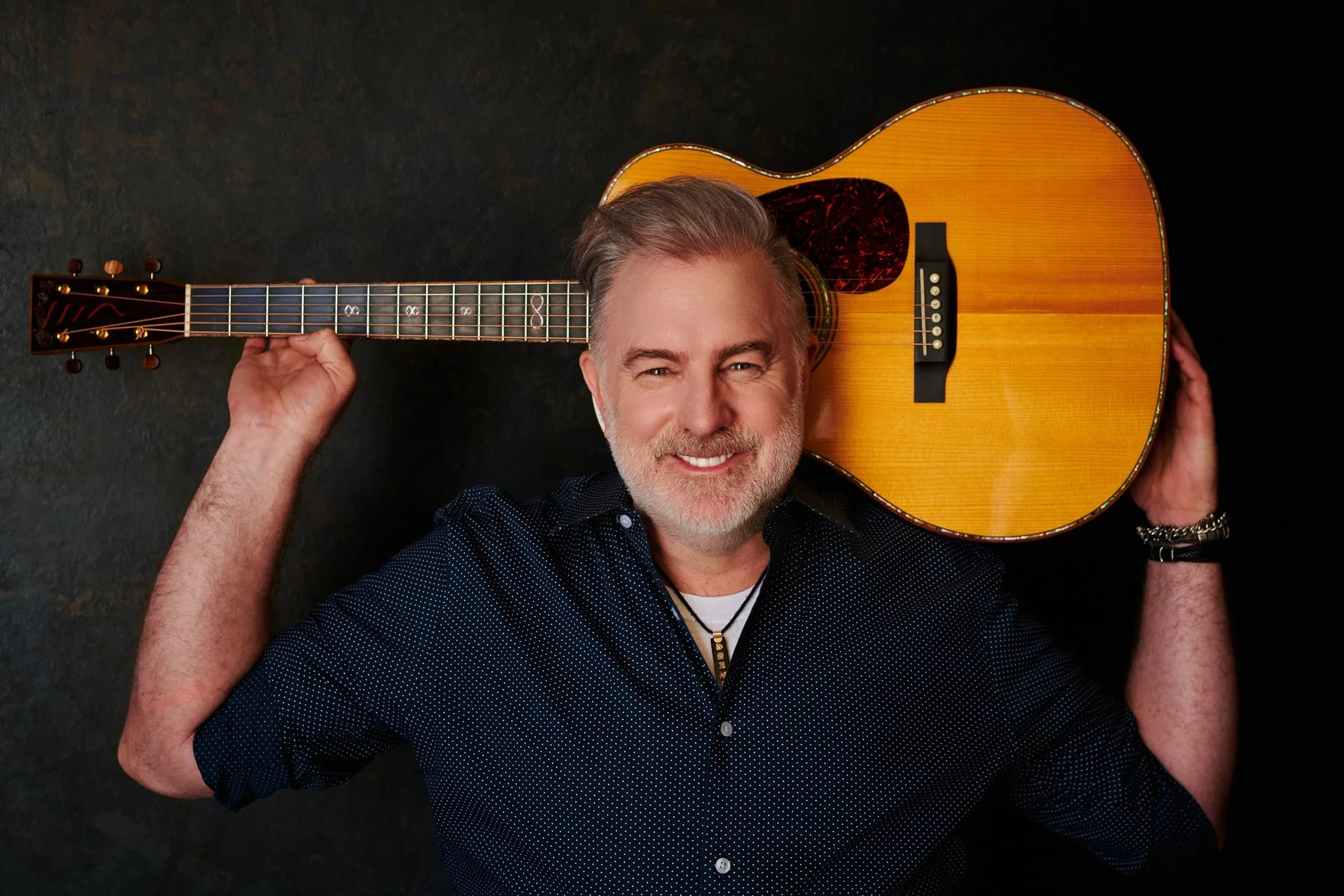 Shane Adams, songwriter and producer, with an acoustic guitar