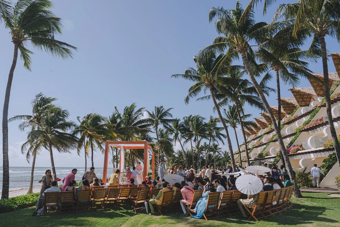 A sunlit beachfront wedding, unfolding under white parasols and palms, seamlessly planned by Preeti Exclusive Events.