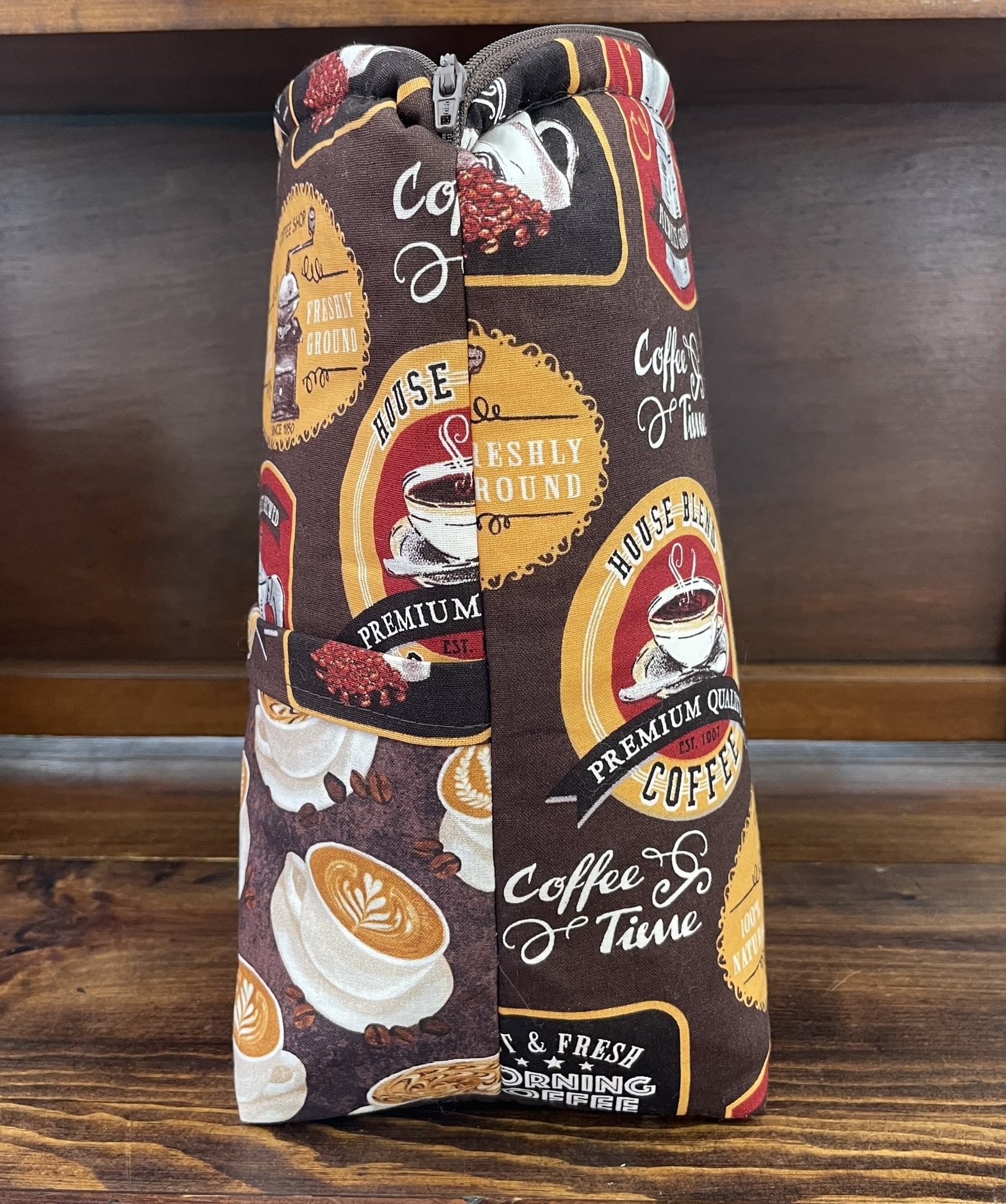 Side view of a large coffee-themed project bag, featuring retro coffee advertisements and cups, with a practical side handle for easy carrying.