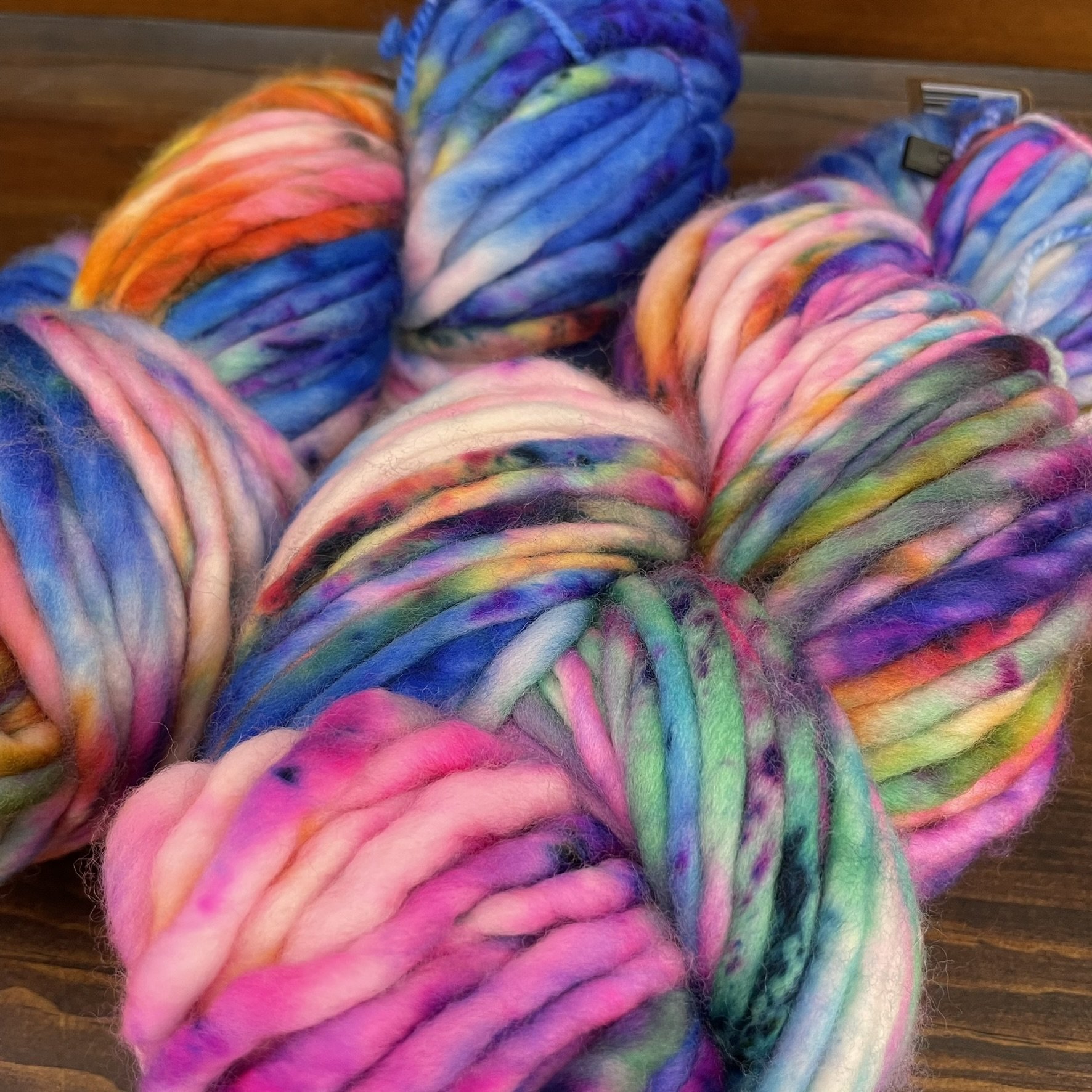 Close-up view of Honey & Clover Super Bulky yarn in I Can't Feel My Face, showing vibrant swirls of pink, purple, blue, and orange.