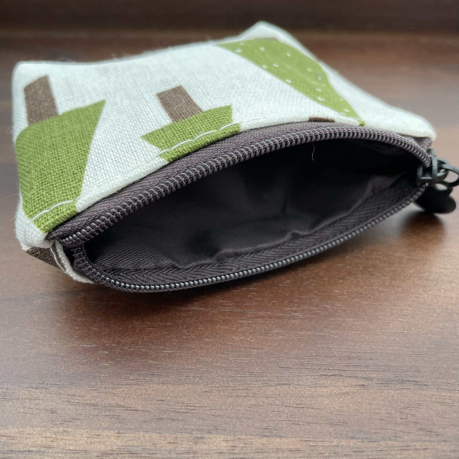 Small fabric pouch with a green tree design, shown with the zipper open.