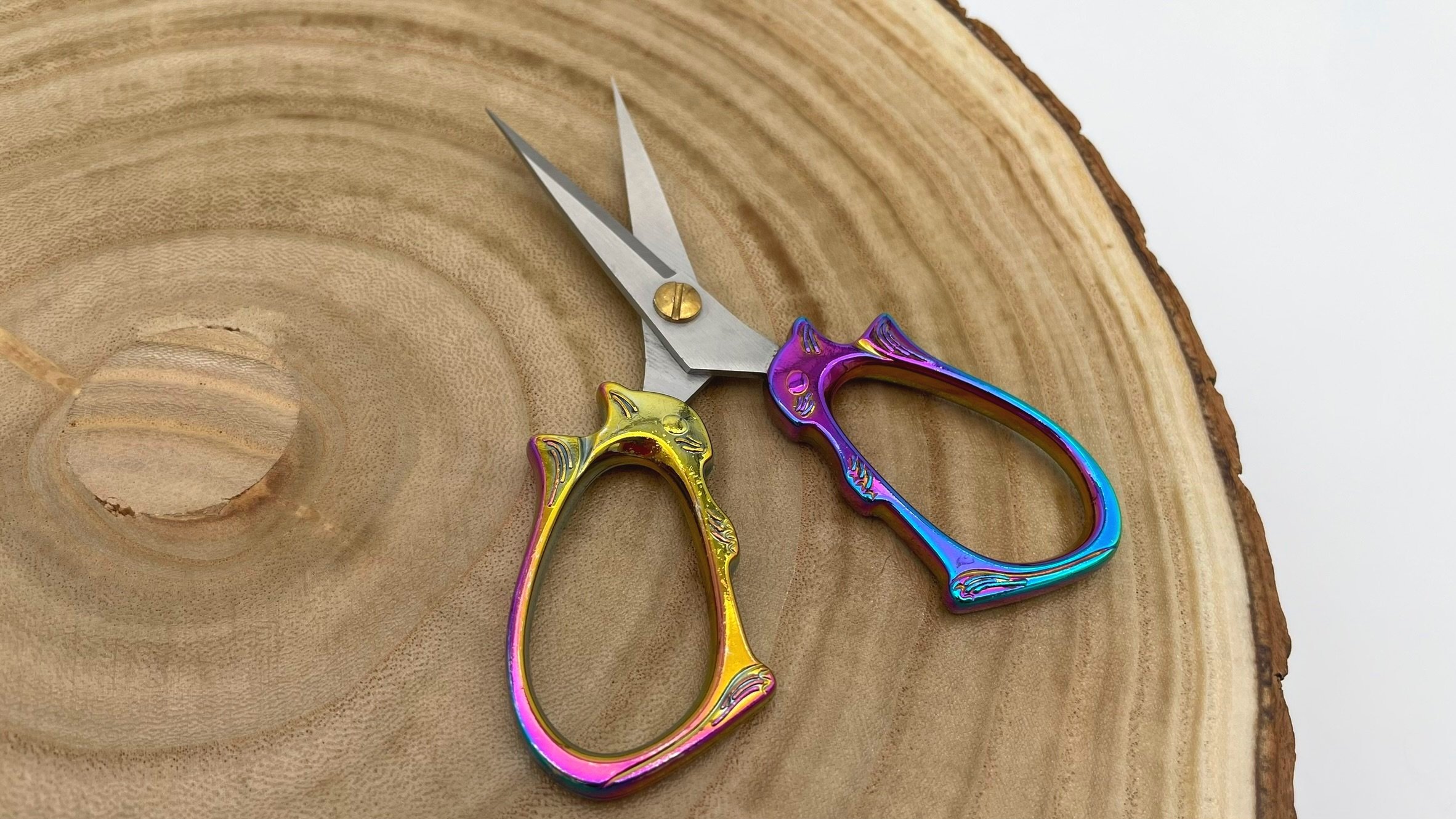 Multicolor rainbow squirrel embroidery scissors on a wood surface, designed for precise cuts in crafting and embroidery.