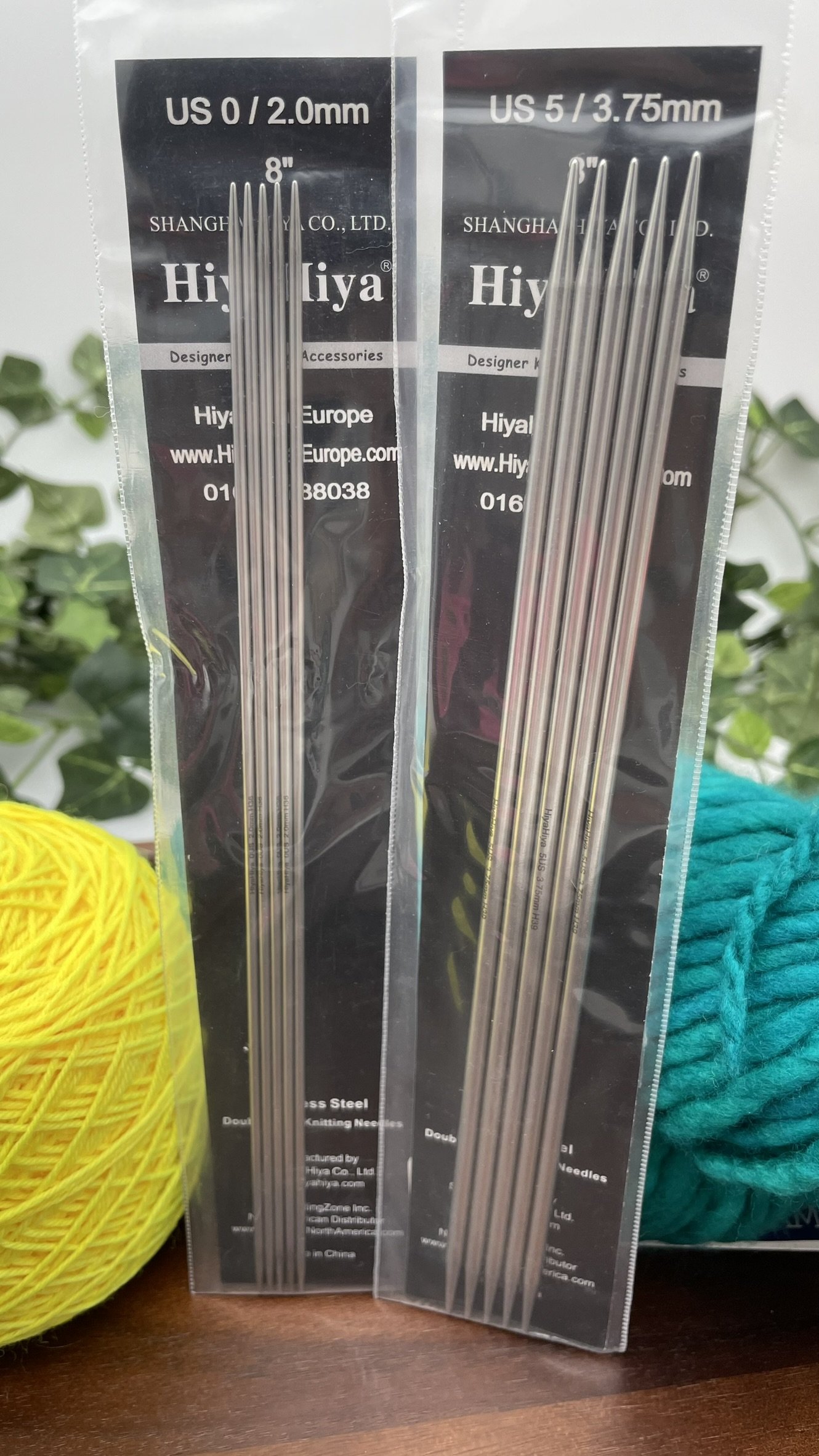 Two packages of HiyaHiya 8-inch steel double-pointed knitting needles displayed with yarn