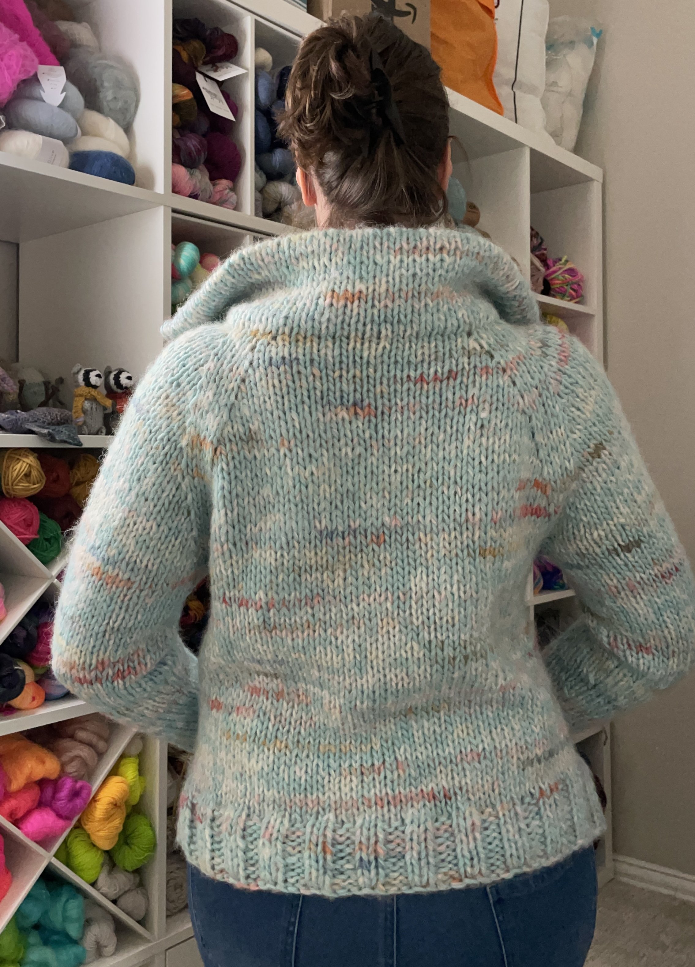 Back view of a hand-knit sky blue Wishlist pullover modeled, highlighting the cozy fit and vibrant colors.