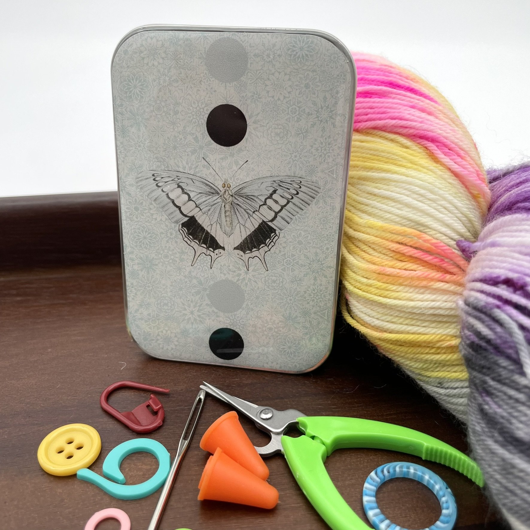 Standing notions tin with intricate blue moth design and knitting tools