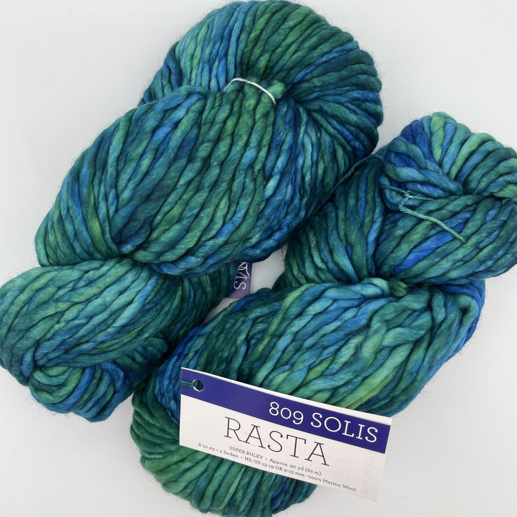 Skein of Malabrigo Rasta yarn in Solis color, showcasing blue and green hues with a super bulky texture, 100% Merino wool.