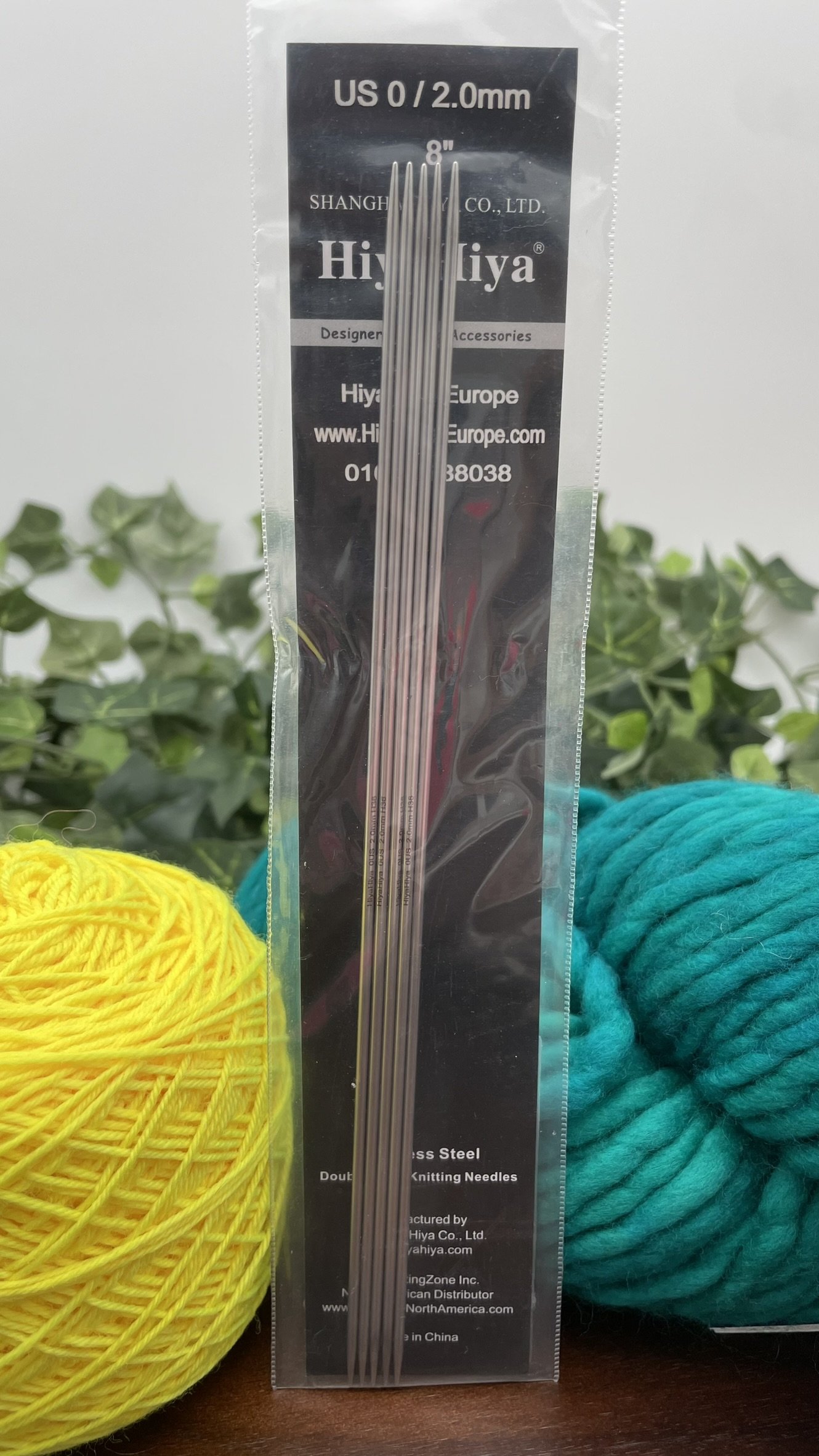 HiyaHiya 8-inch steel double-pointed knitting needles with yarn displayed on a wooden surface