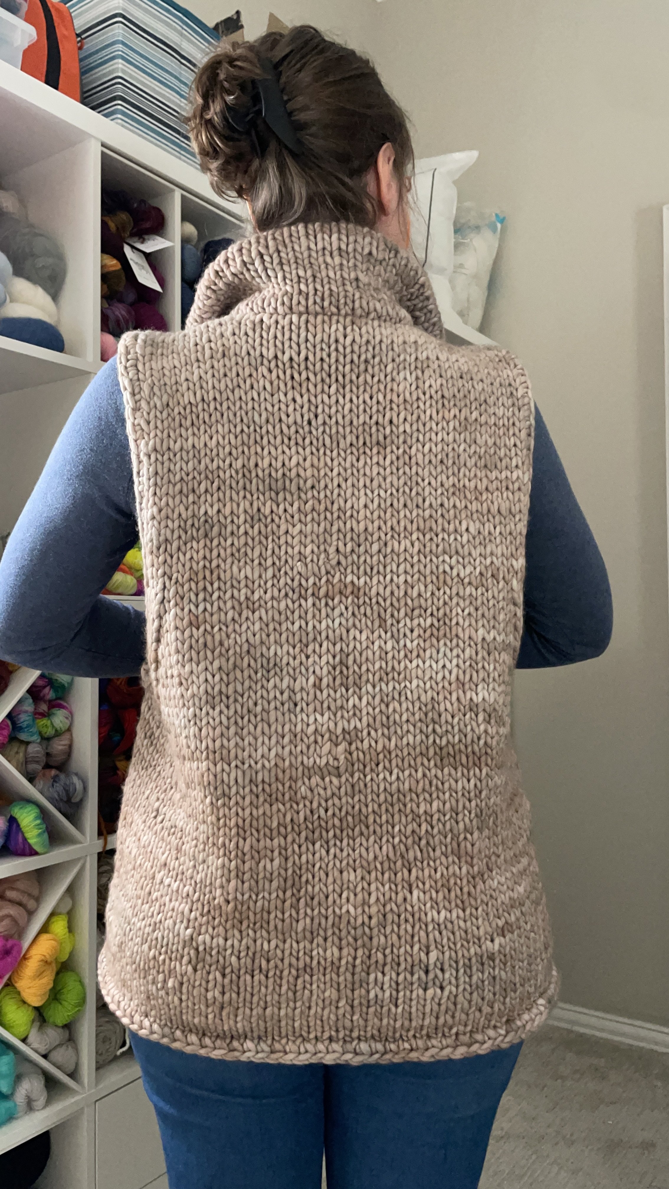 Back view of a hand-knit adventurer vest modeled, highlighting the vest’s texture and length.