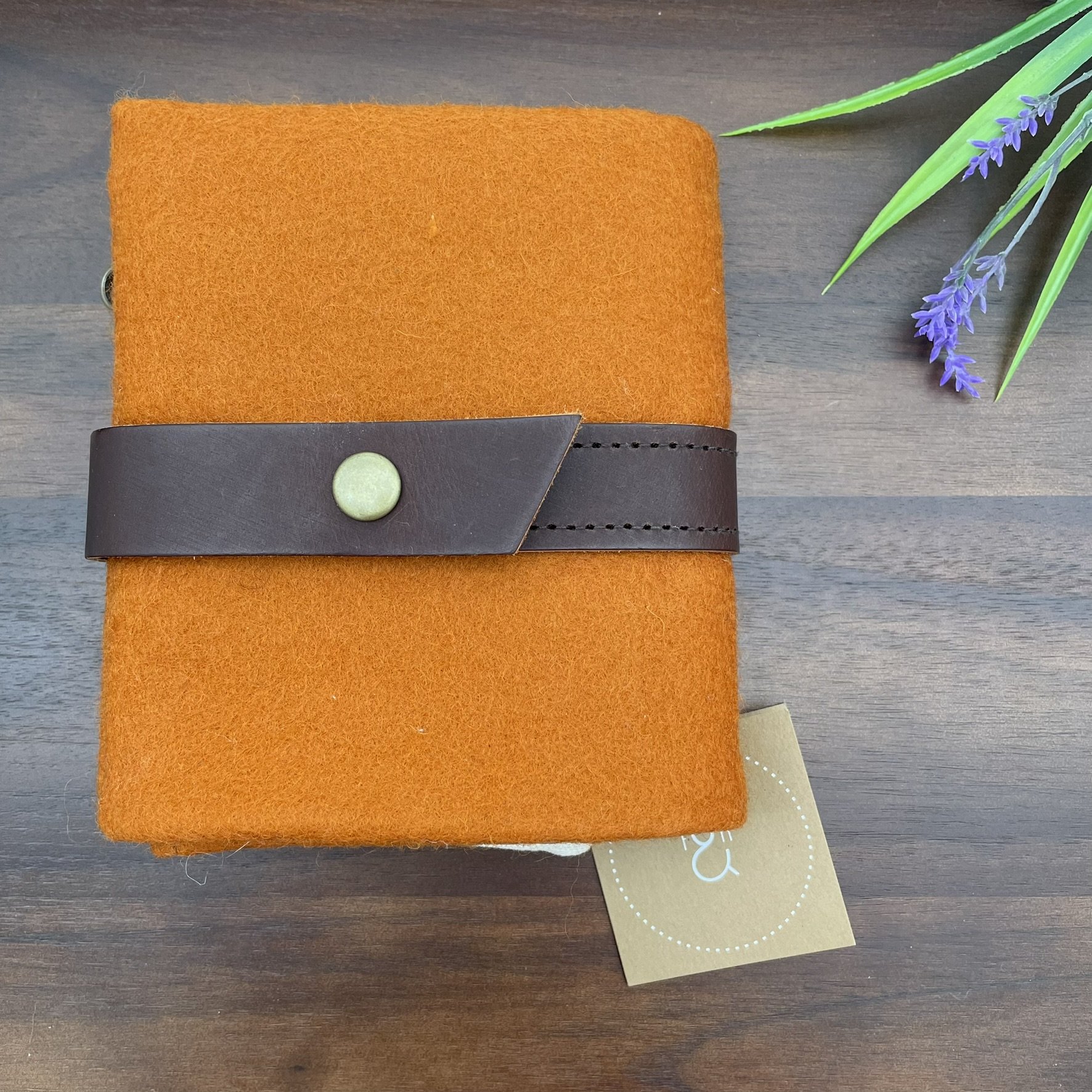 Front view of the Twig & Horn orange wool knitting tool pouch, with a brown leather strap and brass button closure.