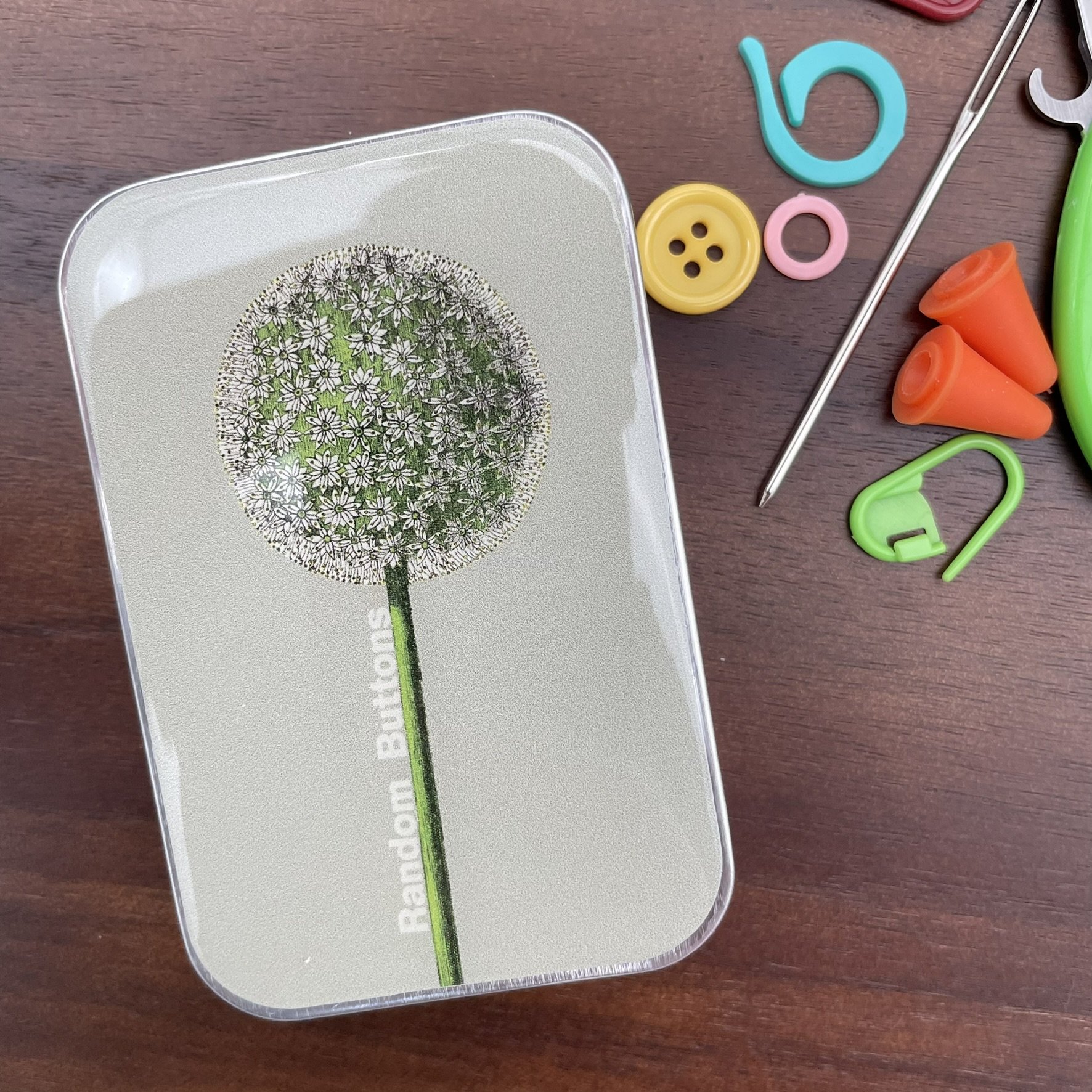 Notions tin with a minimalist dandelion design labeled "Random Buttons," perfect for storing knitting and sewing accessories. Created by Firefly Notes.