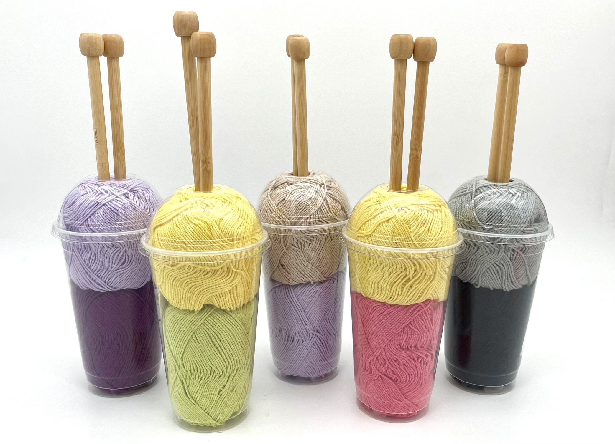 DIY Smoothie Scarf Knitting Kit by Knitca, showcasing five yarn cups in multiple colors with wooden knitting needles.