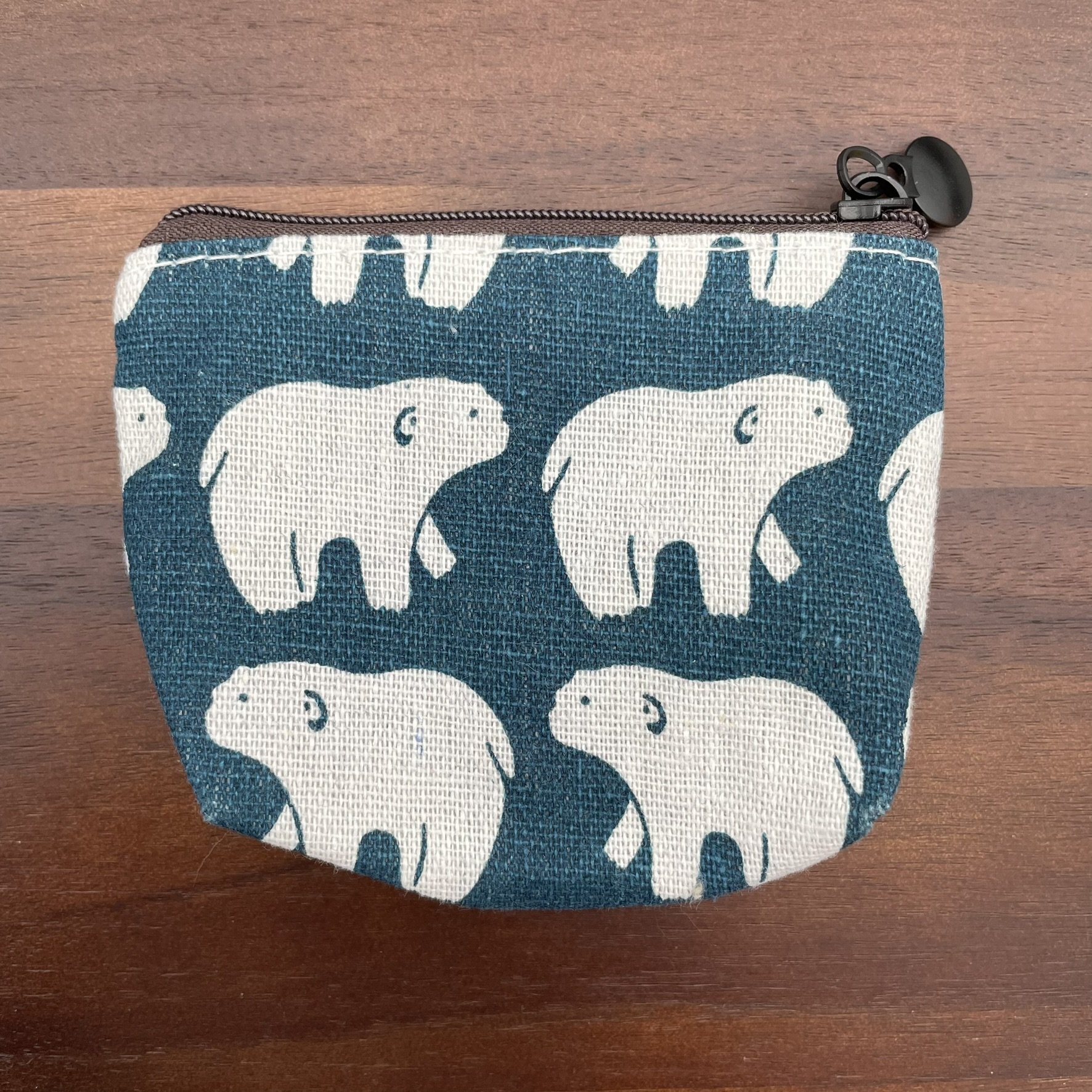 Small fabric pouch with white polar bear print on a blue background, featuring a zipper closure.