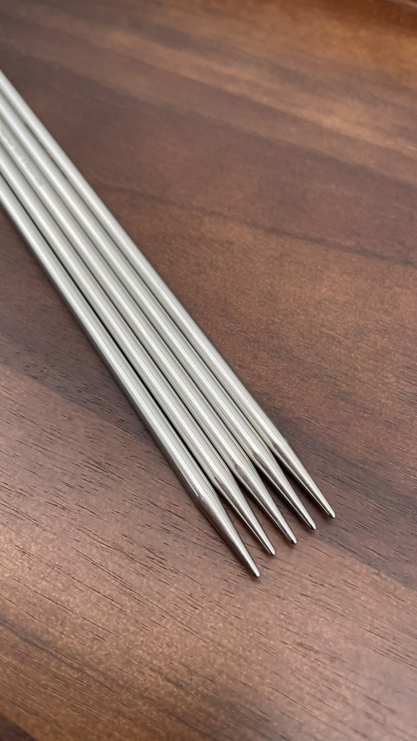HiyaHiya 8-inch steel double-pointed knitting needles displayed on a dark wooden surface