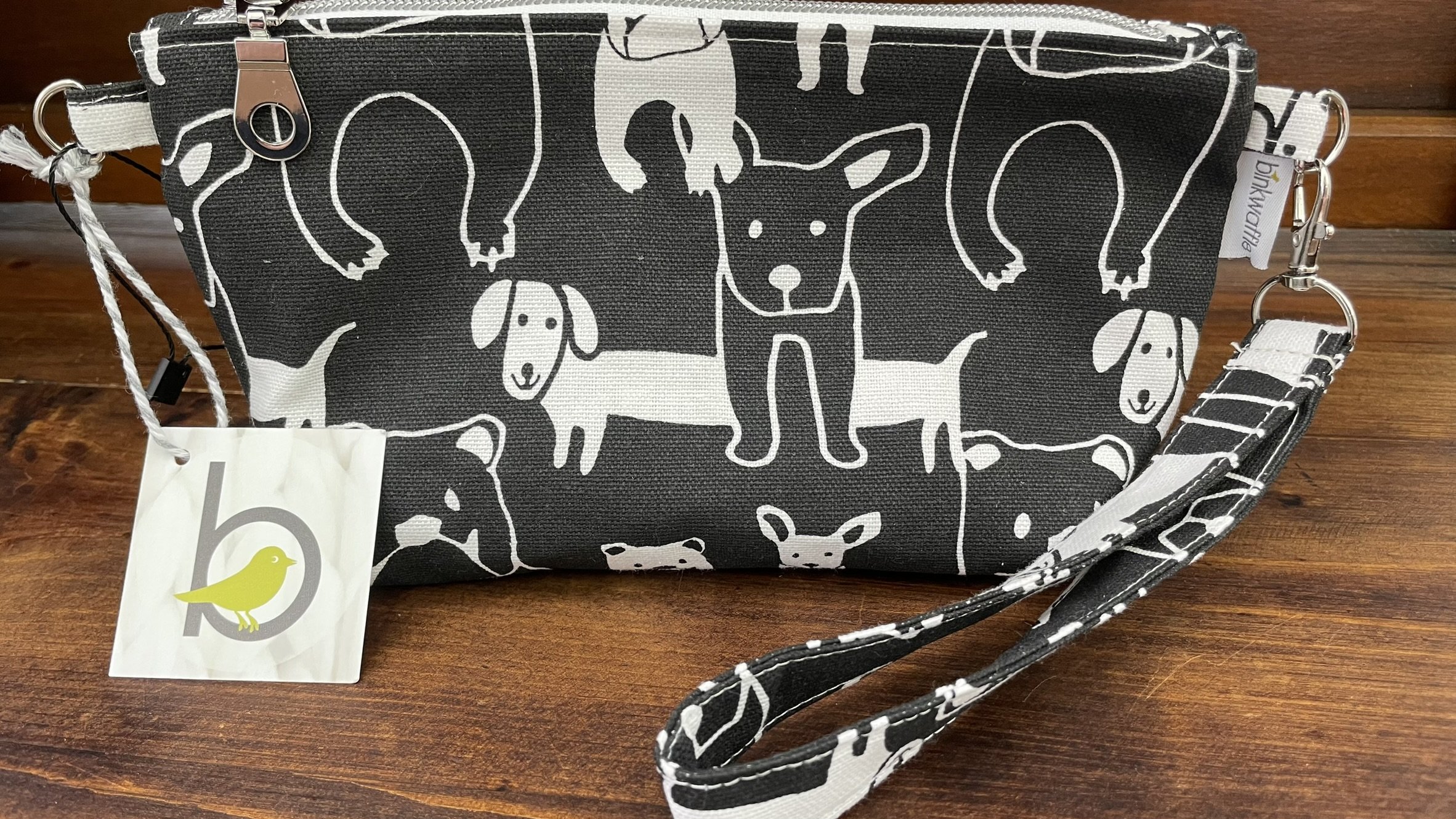 Black and white zippered accessories pouch with playful dog illustrations, featuring durable fabric and a wrist strap for easy carrying.