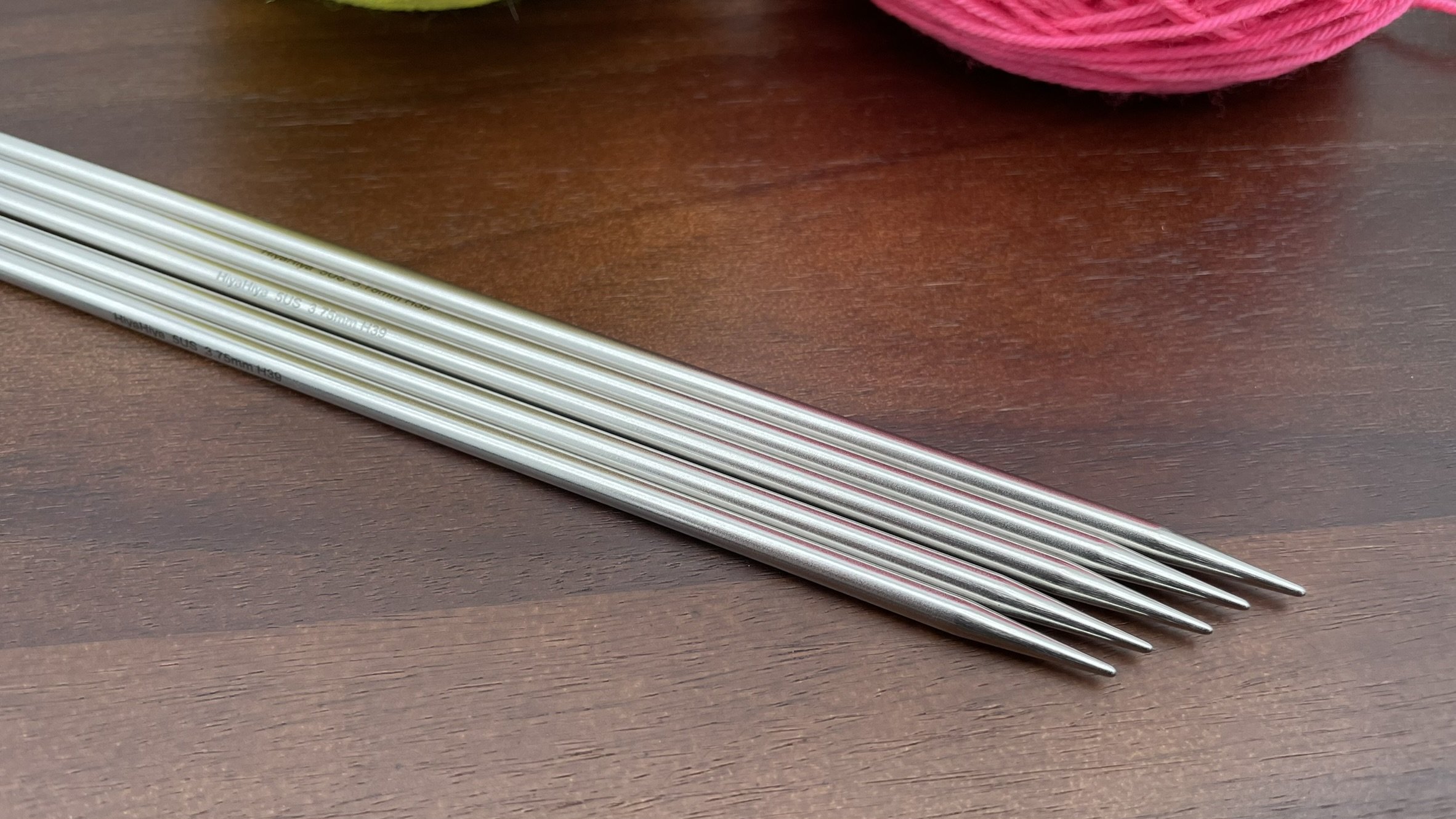 Close-up of HiyaHiya 8-inch steel double-pointed knitting needle tips displayed on a wooden surface