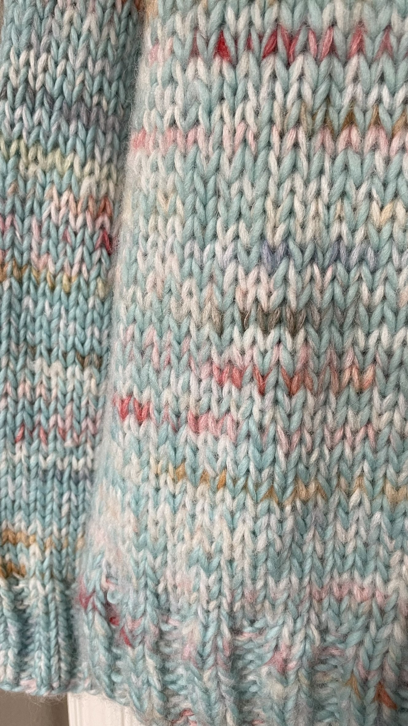 Close-up of the knit stitch detail on the hand-knit Wishlist pullover, showing colorful speckles on sky blue wool.