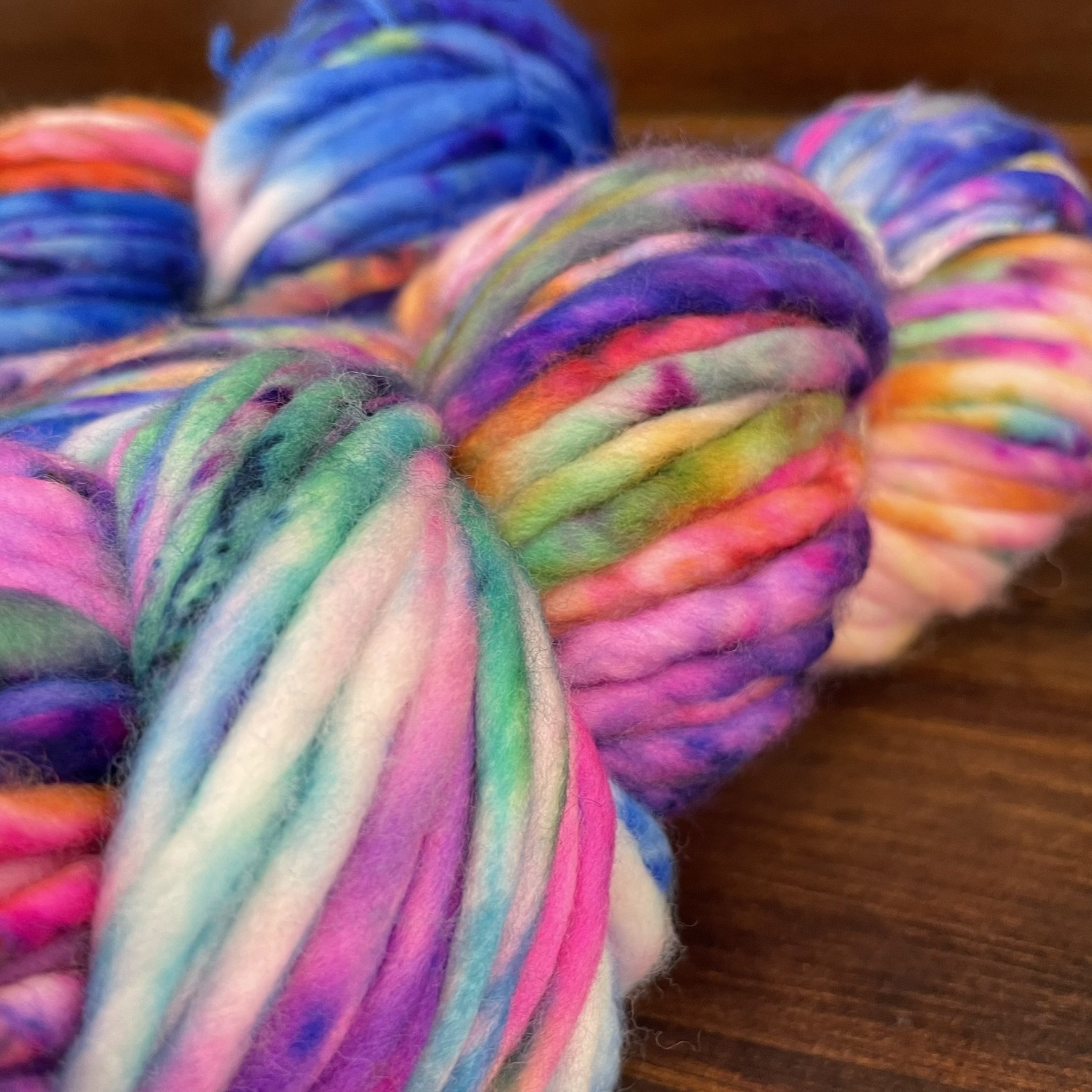 Angled view of Honey & Clover Super Bulky yarn in I Can't Feel My Face colorway, featuring bold and bright multicolor strands.