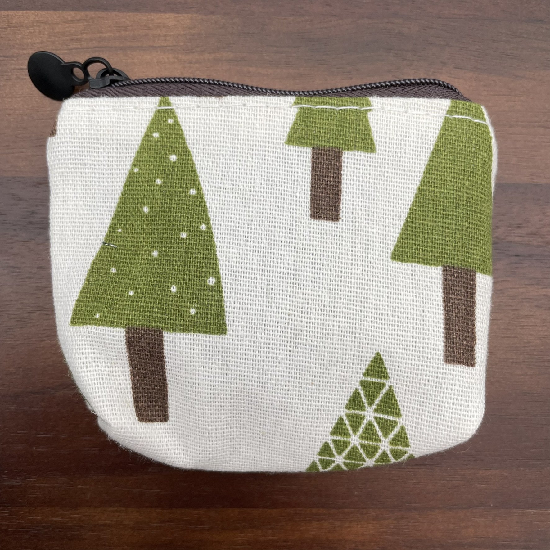 Small fabric pouch with green tree design, featuring a zipper closure.