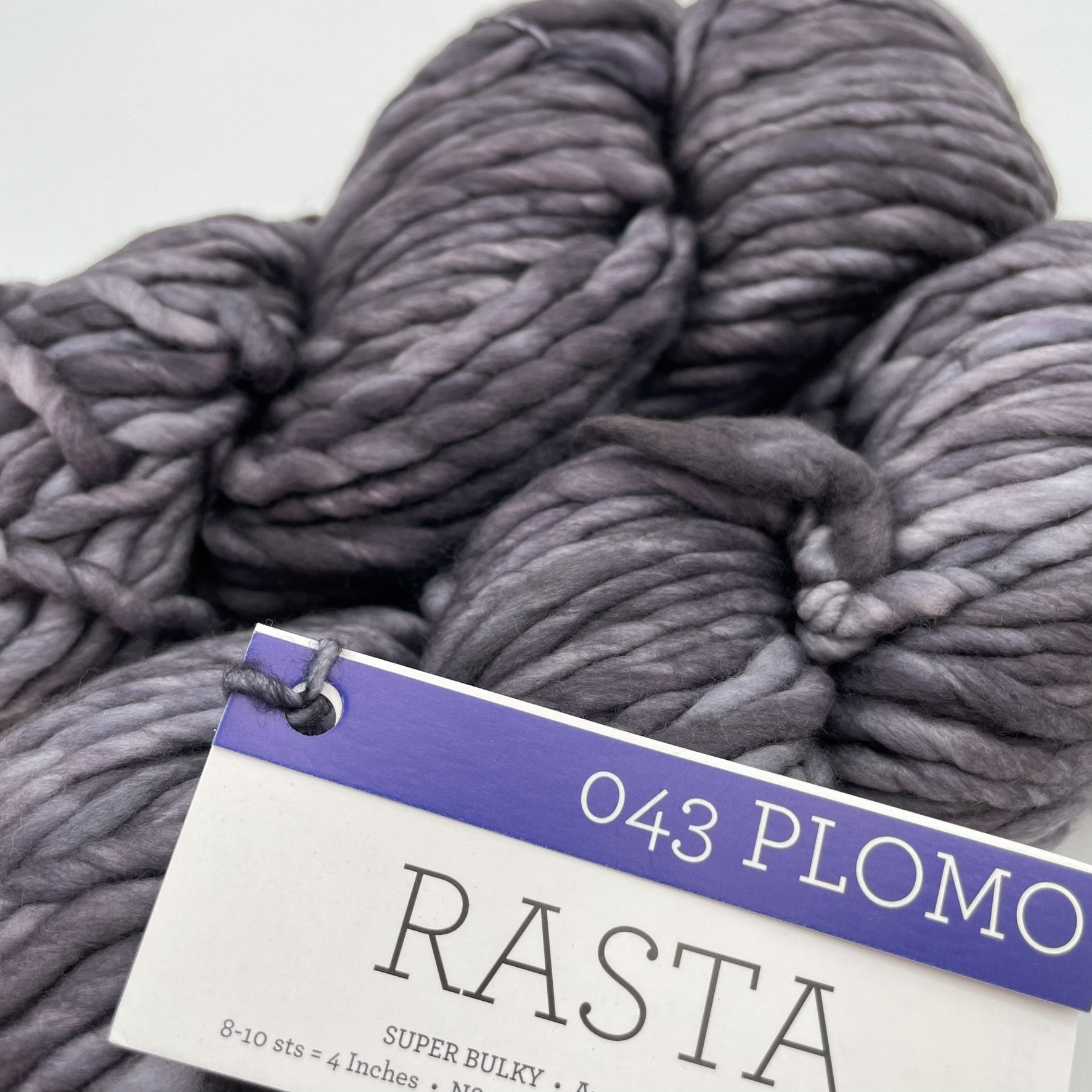 Close-up view of Malabrigo Rasta yarn in Plomo color, highlighting the smooth texture and subtle gray tones, 100% Merino wool.