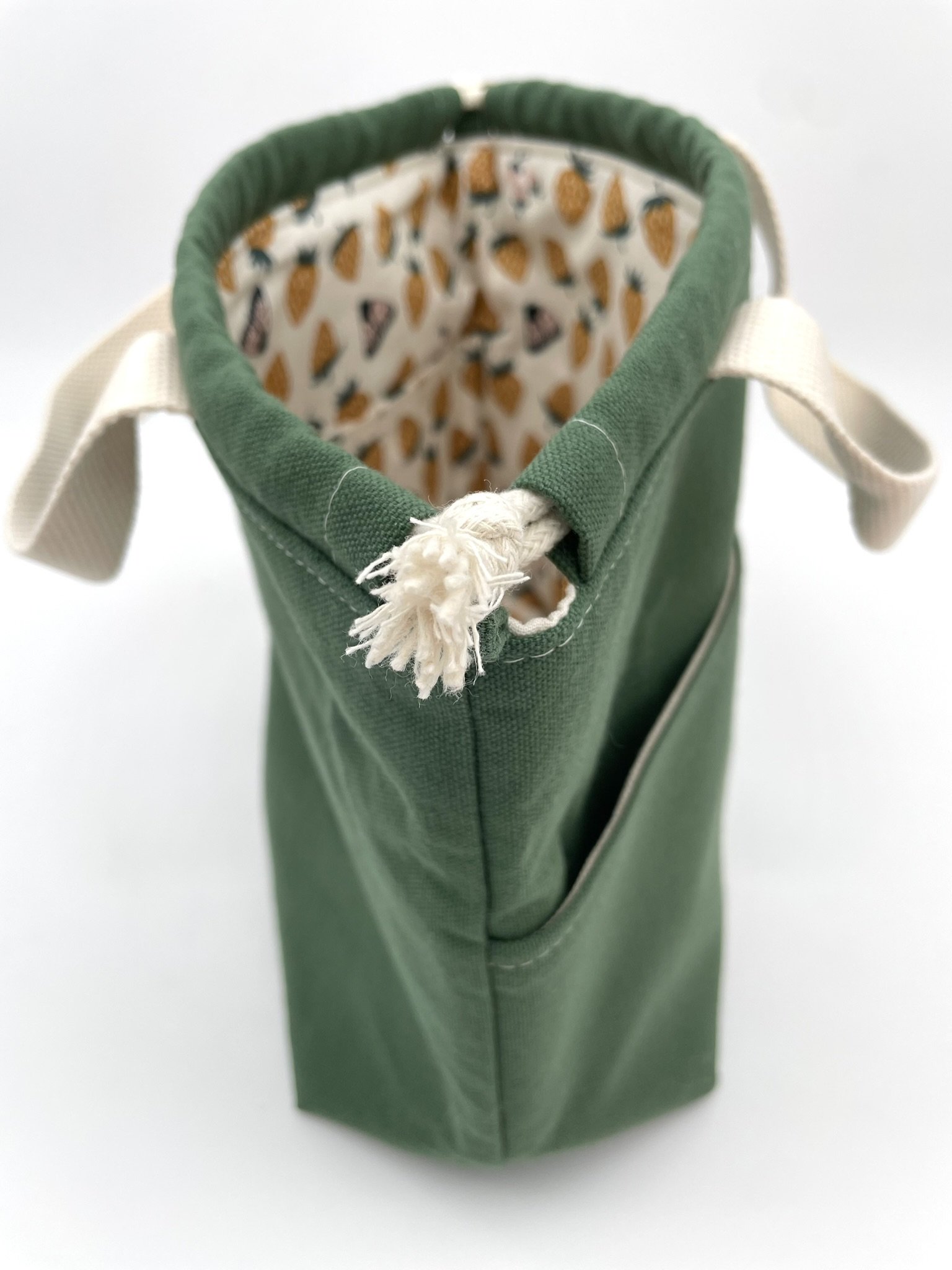 Side-top view of the small green Puff Stitch project bag with drawstring and handle.