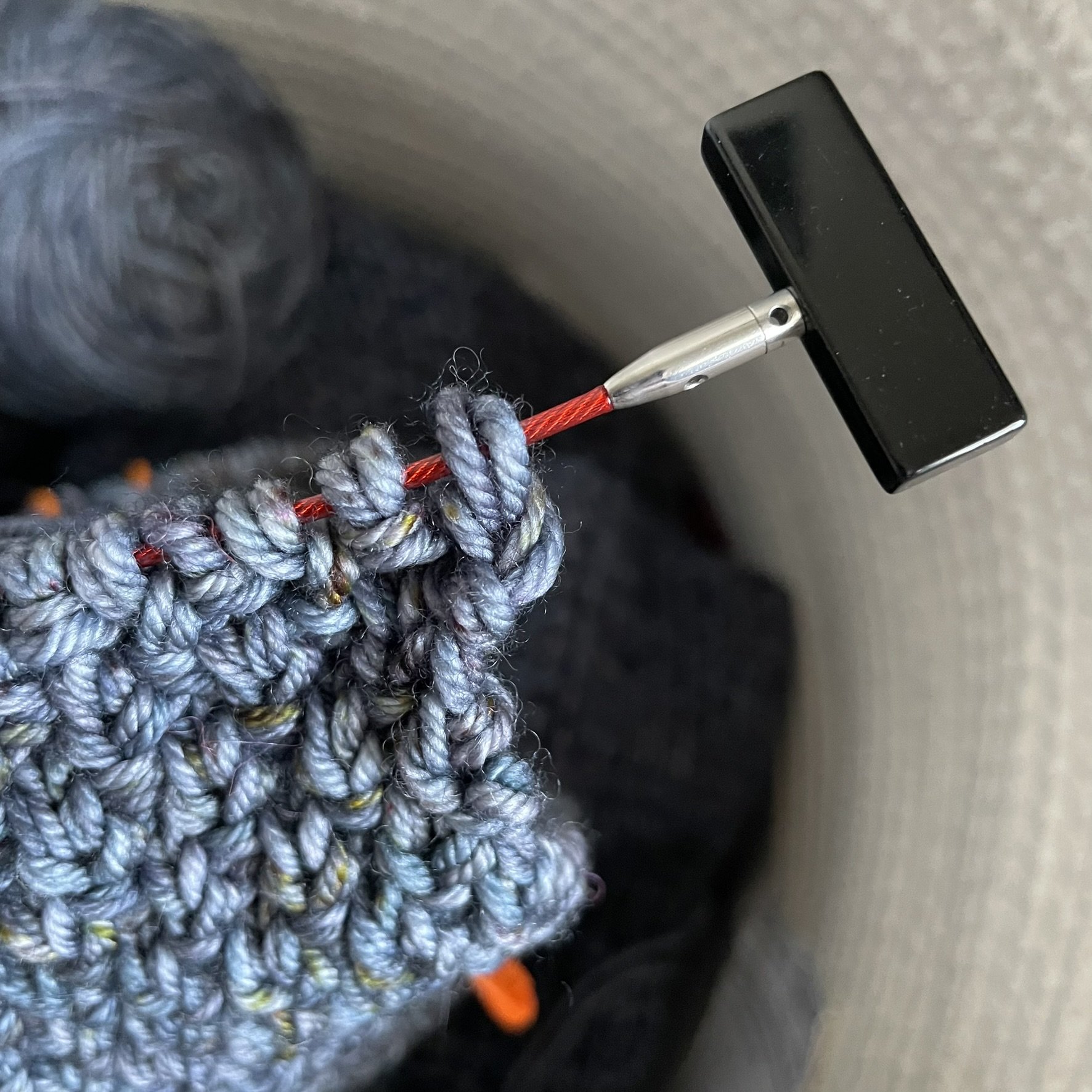 ChiaoGoo large end stopper attached to a knitting project, securing stitches on the cable