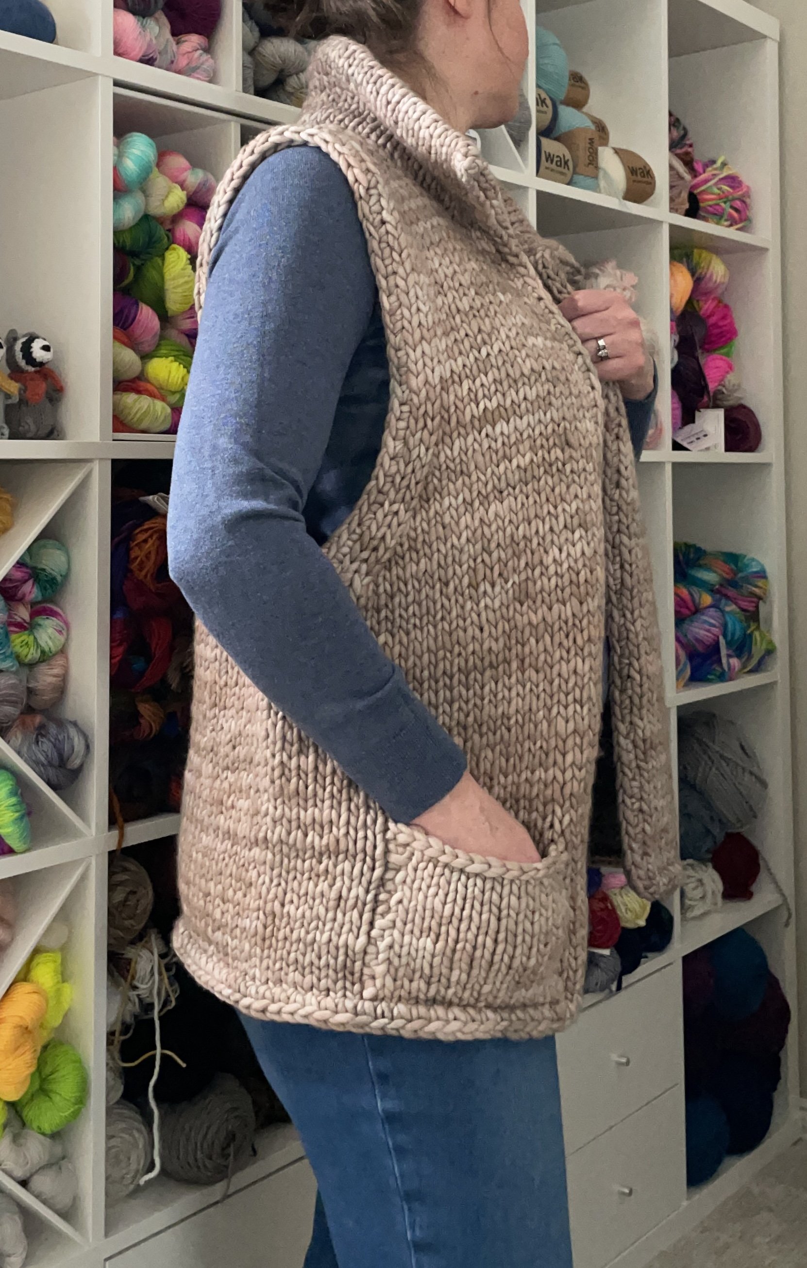 Side view of a hand-knit adventurer vest modeled, showing the pocket detail and side fit.