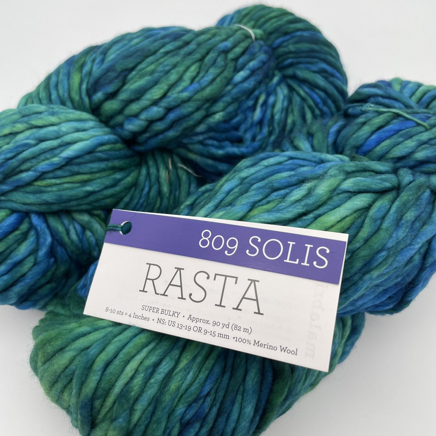Angle view of Malabrigo Rasta yarn in Solis color, featuring vibrant shades of blue and green, super bulky, 100% Merino wool.